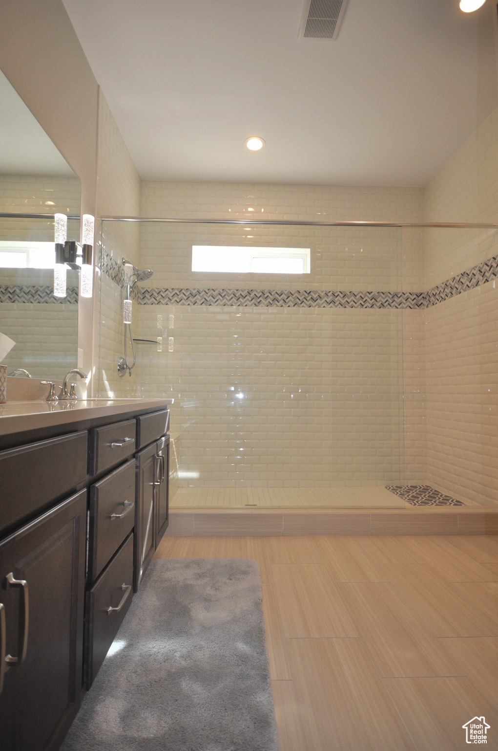 Bathroom with tile floors, vanity, and tiled shower