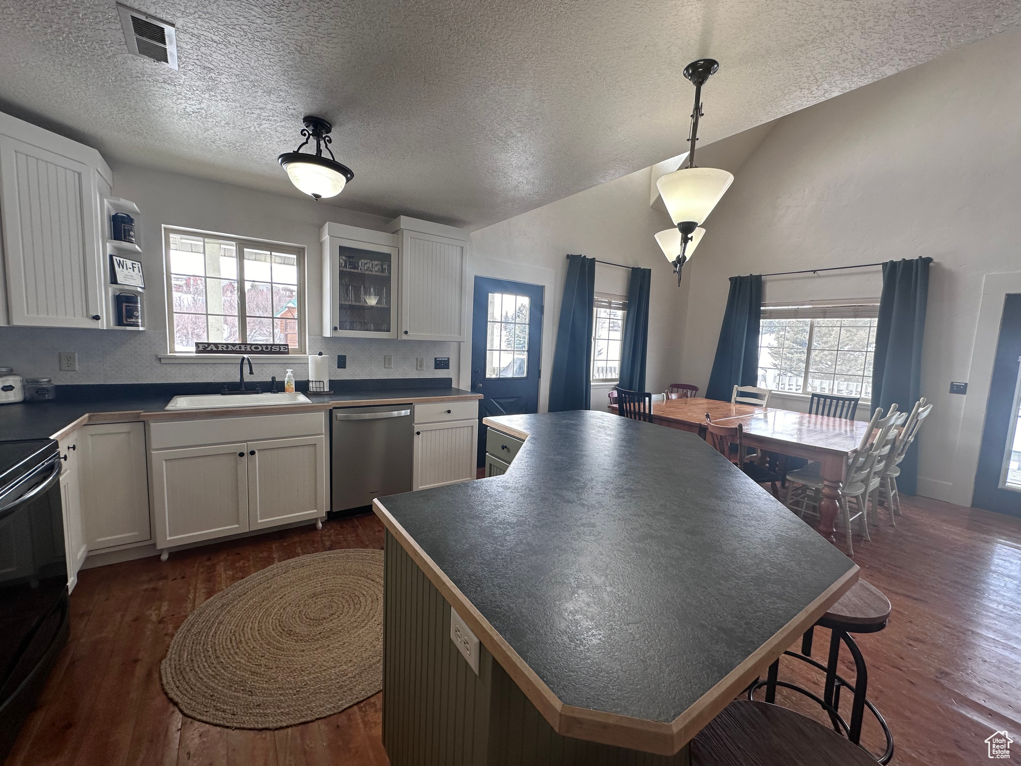 Kitchen with sink, white cabinets, hanging light fixtures, dishwasher, and hard wood  flooring
