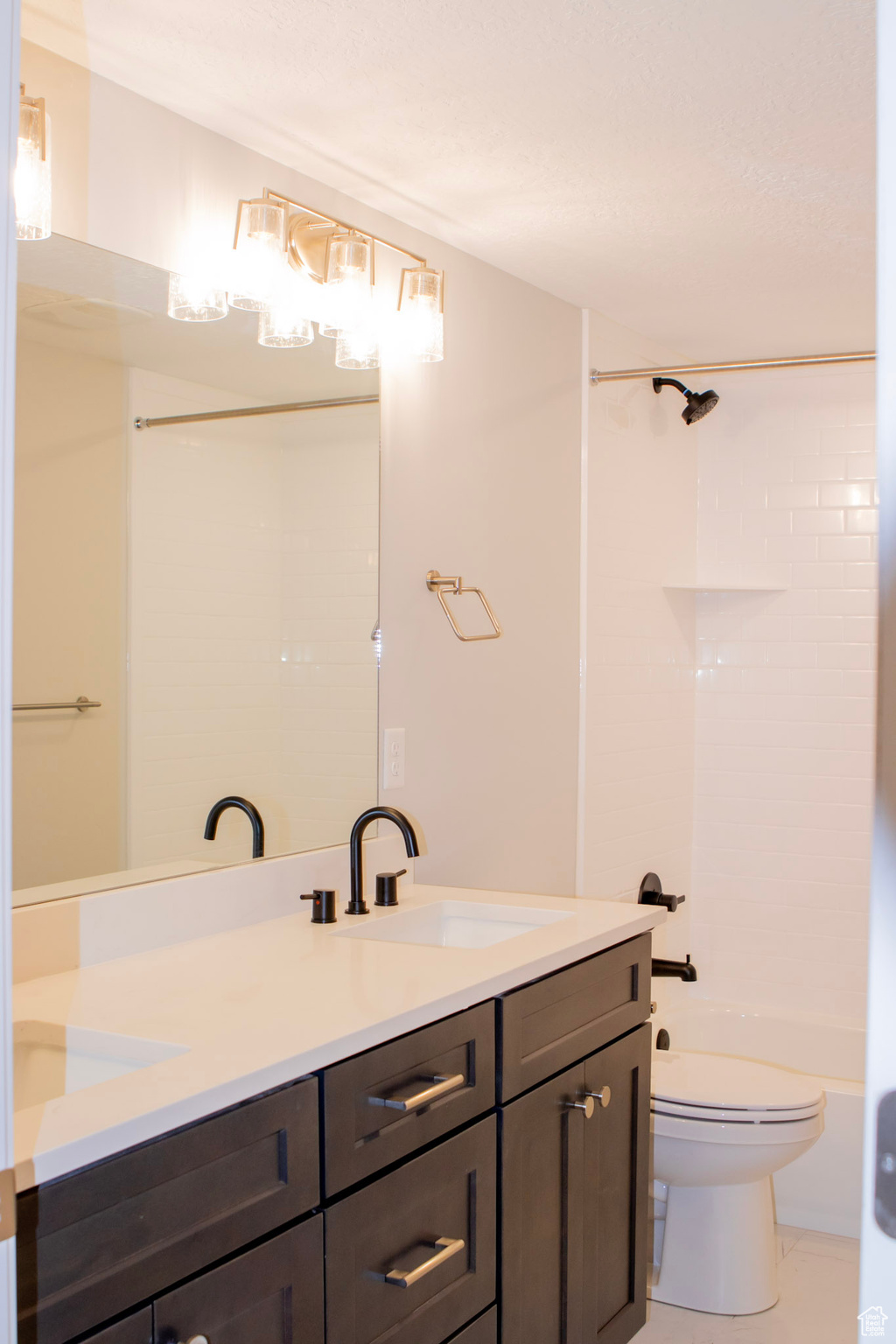 Full bathroom with double sink vanity, tile floors, toilet, and  shower combination