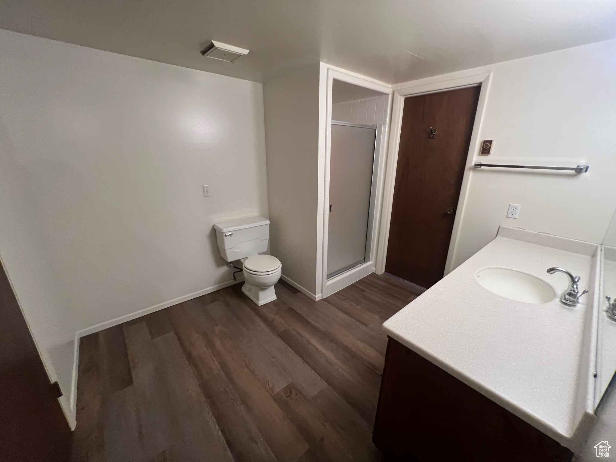 Bathroom with vanity, hardwood / wood-style flooring, toilet, and a shower with door