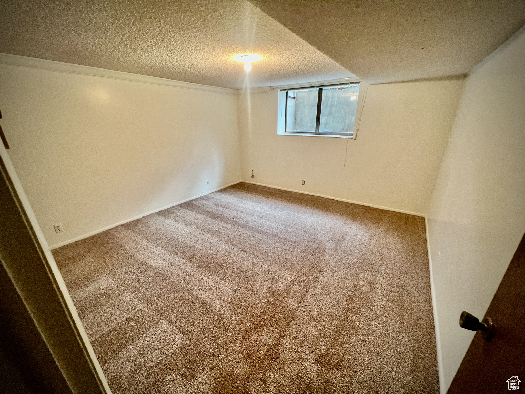 Empty room with carpet floors and a textured ceiling