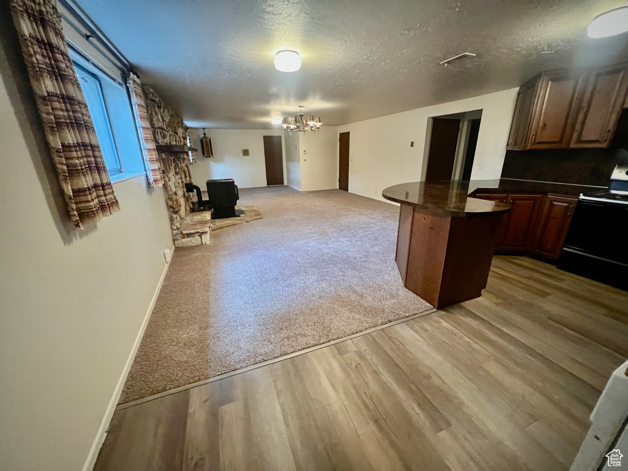 Kitchen featuring a notable chandelier, black electric range oven, a textured ceiling, and light hardwood / wood-style flooring