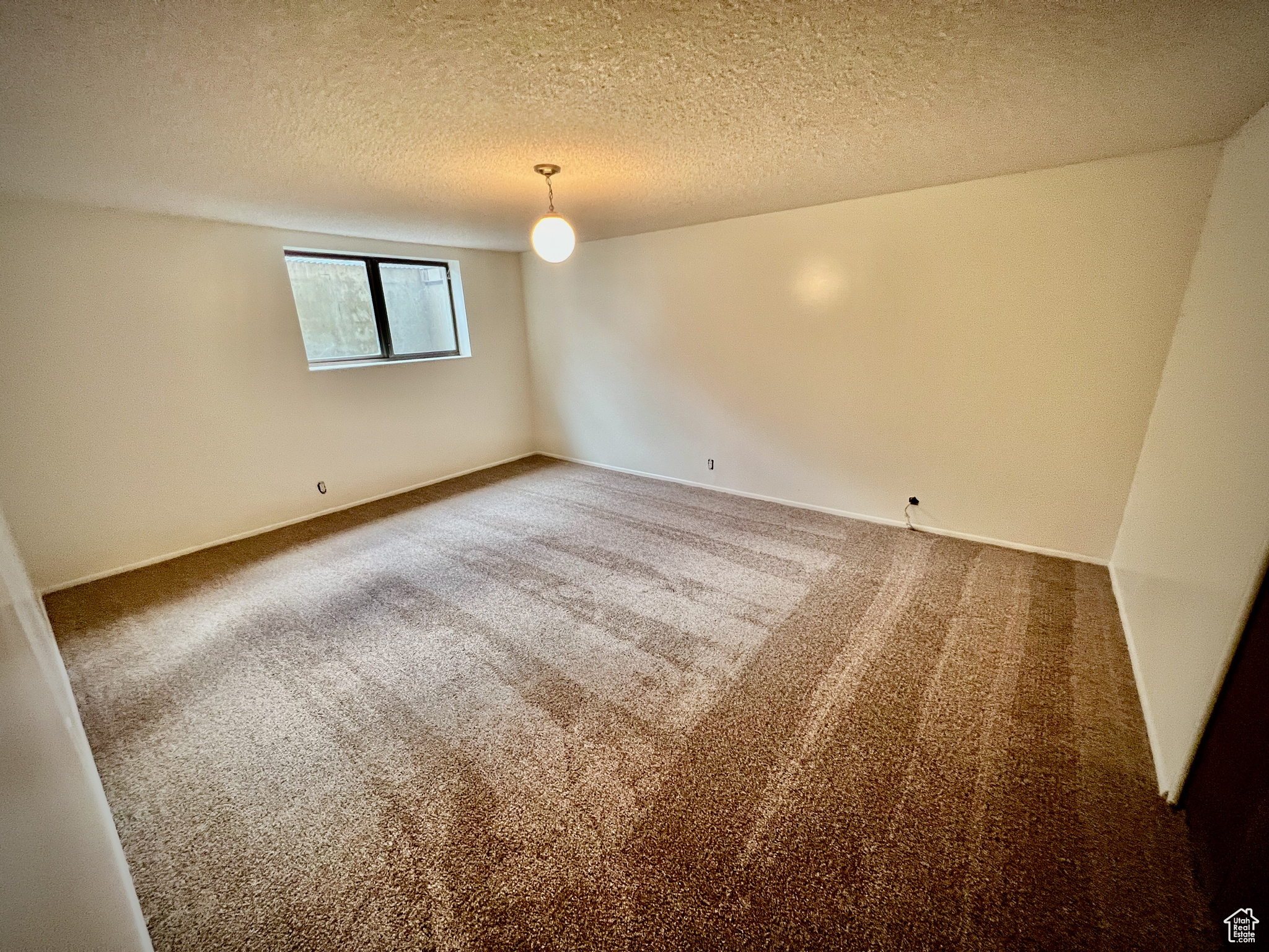 Carpeted spare room featuring a textured ceiling