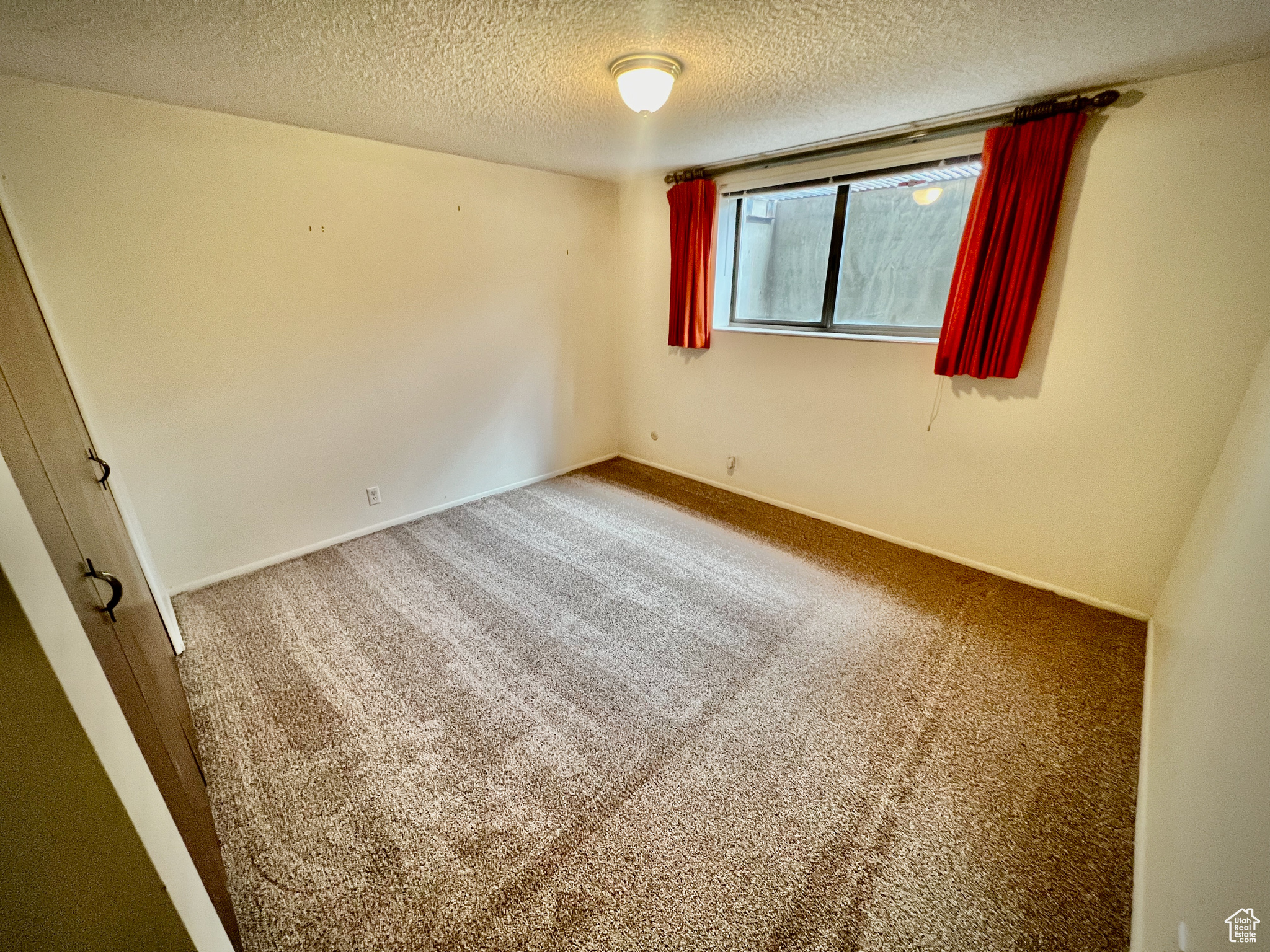 Carpeted spare room with a textured ceiling