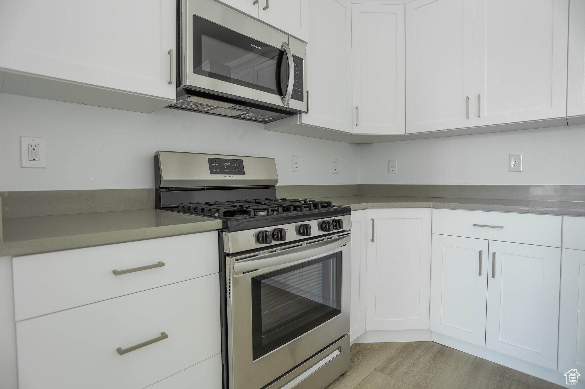 Kitchen featuring appliances with stainless steel finishes, light wood-type flooring, and white cabinets