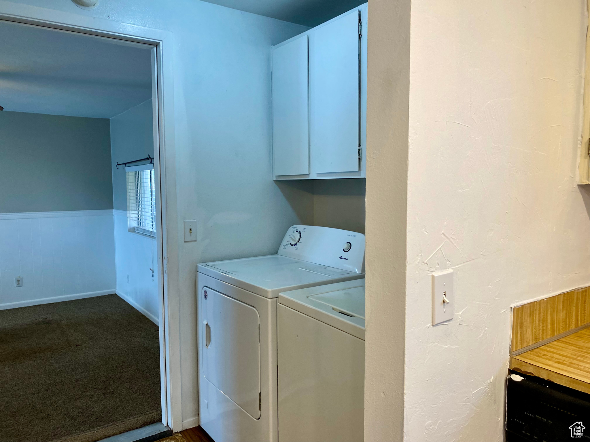 Clothes washing area with separate washer and dryer, dark carpet, and cabinets