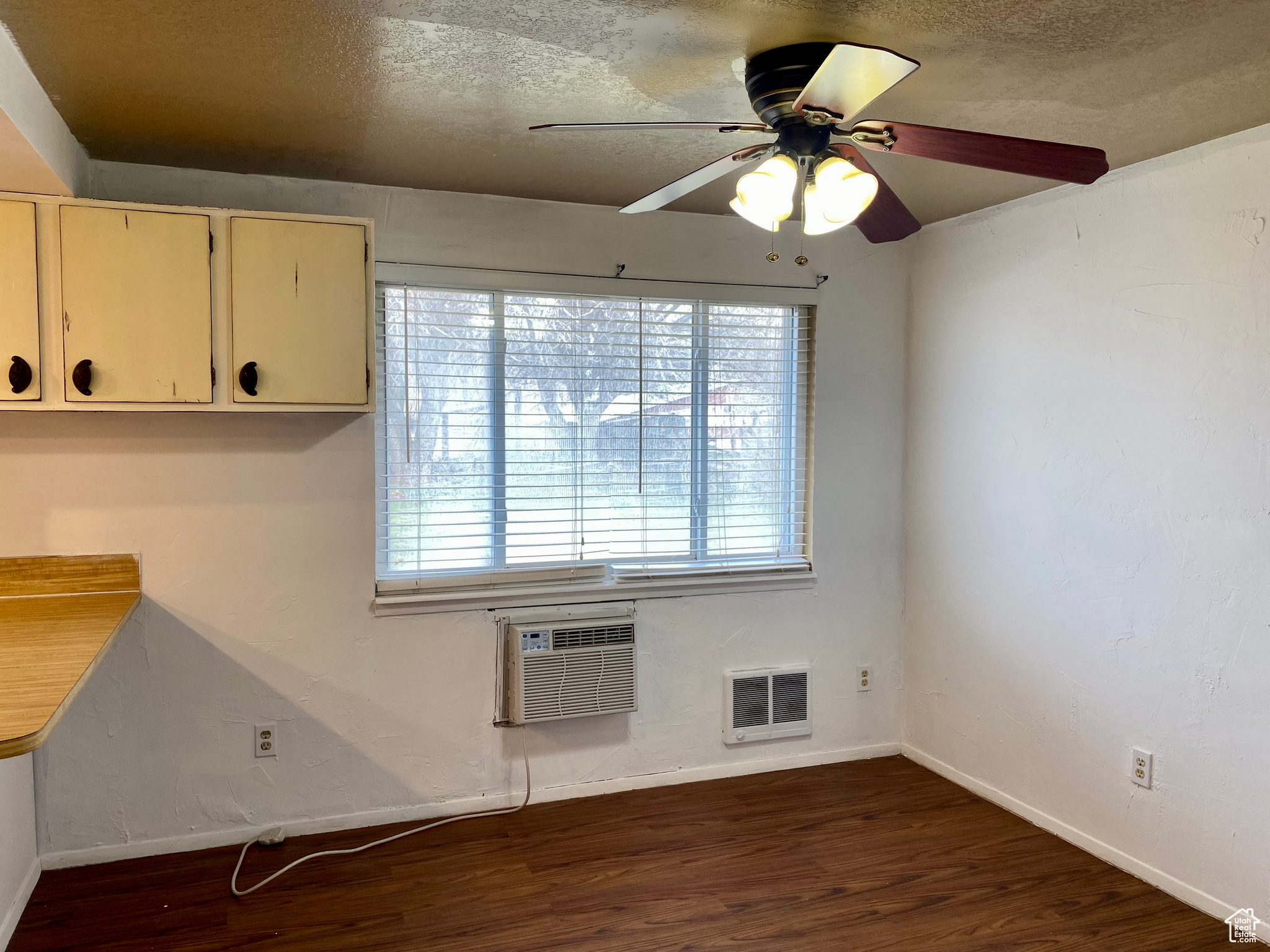 Empty room with a wall mounted air conditioner, dark hardwood / wood-style flooring, a textured ceiling, and ceiling fan