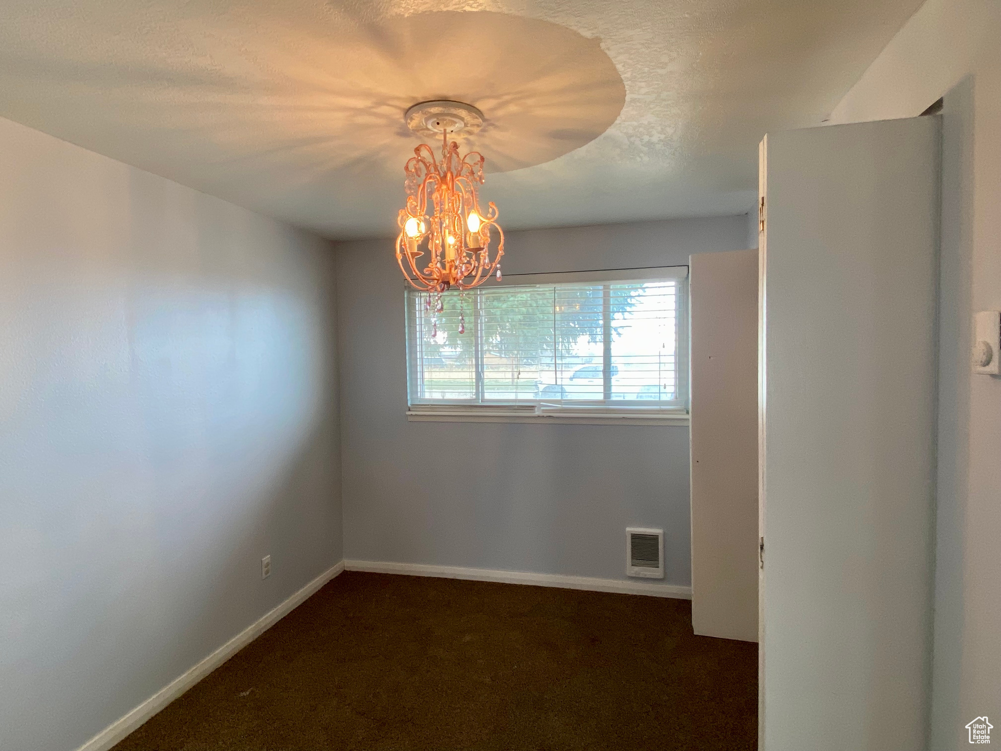 Carpeted spare room with a notable chandelier