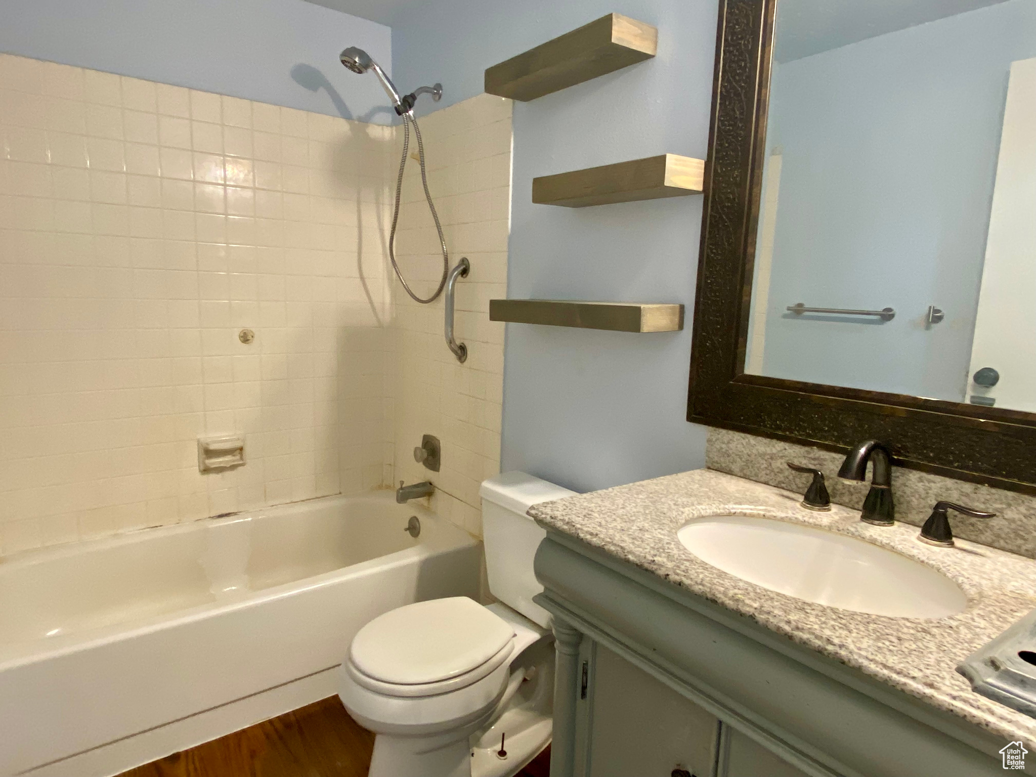 Full bathroom featuring oversized vanity, toilet, tiled shower / bath combo, and hardwood / wood-style floors