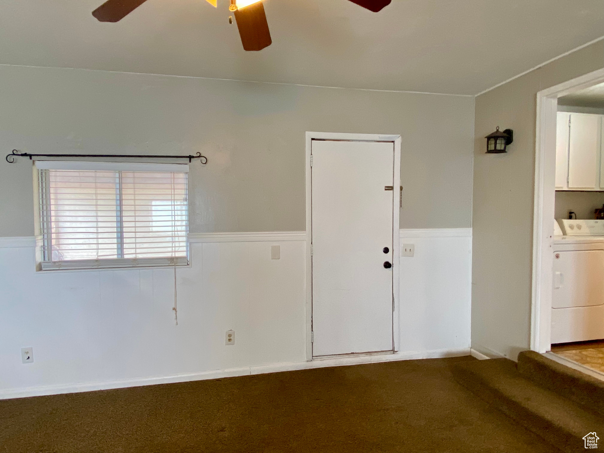 Unfurnished room featuring washer and clothes dryer, dark carpet, and ceiling fan