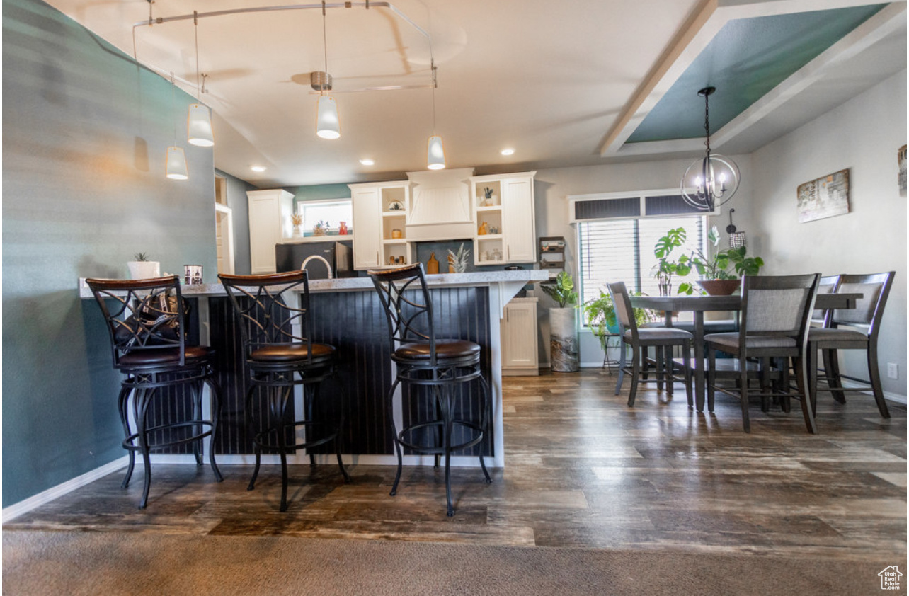 Kitchen featuring dark hardwood / wood-style floors, pendant lighting, a kitchen breakfast bar, and white cabinets