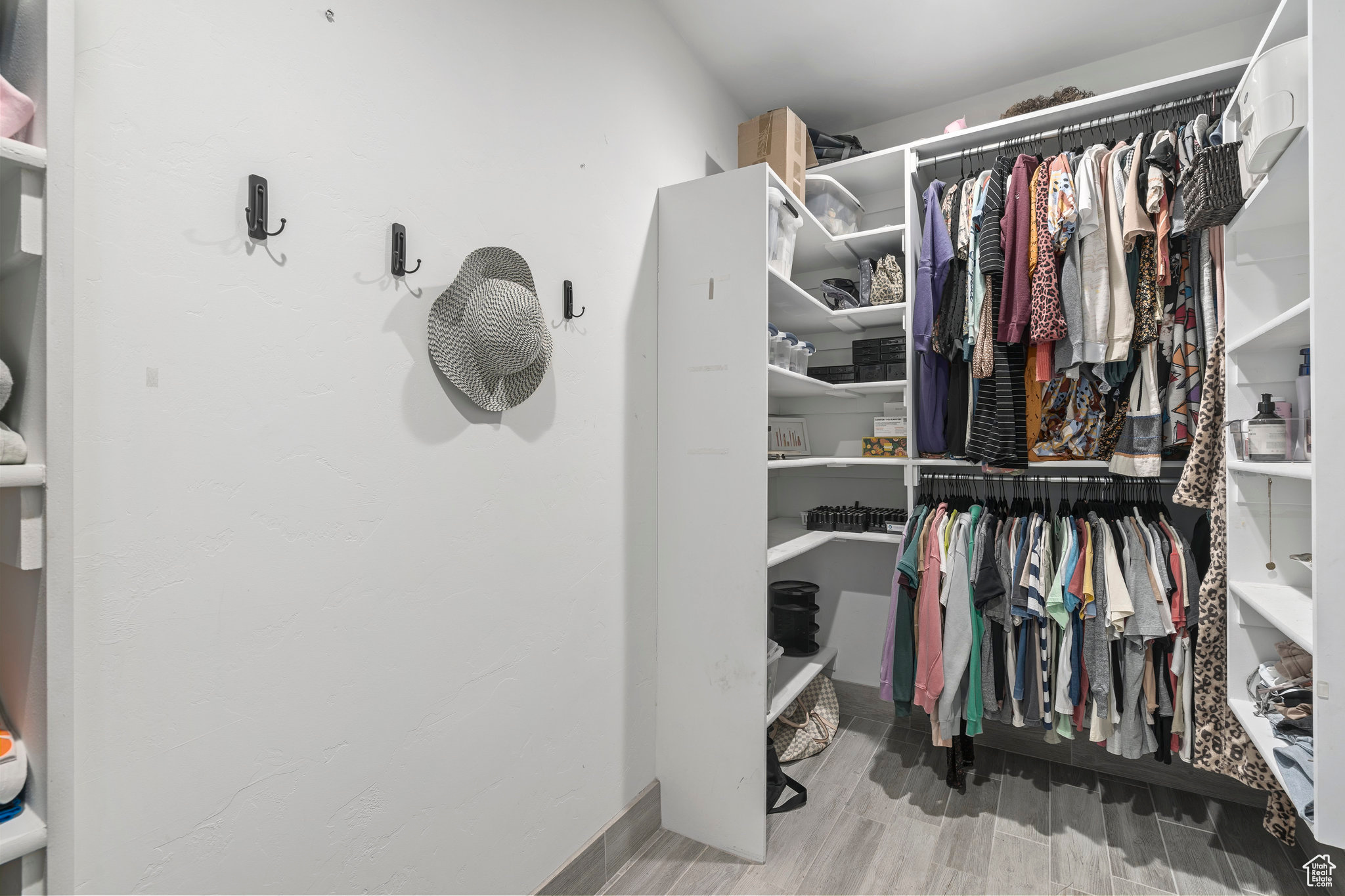 Primary suite walk in closet with light hardwood / wood-style floors