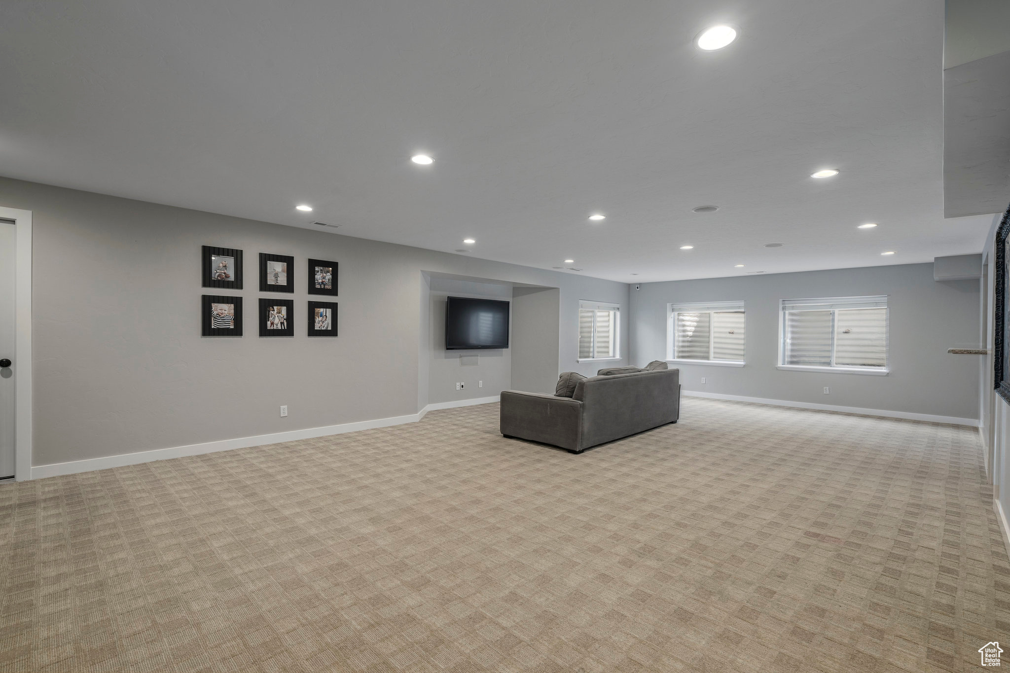 Huge basement living room featuring light colored carpet and a ton of natural light
