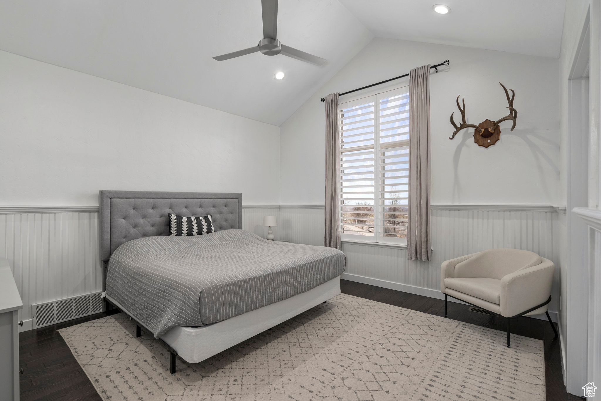 Main level bedroom with lofted ceiling, dark hardwood / wood-style flooring, and ceiling fan