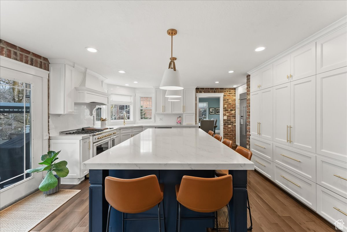 Kitchen featuring a kitchen island, hanging light fixtures, dark hardwood / wood-style floors, and a kitchen bar