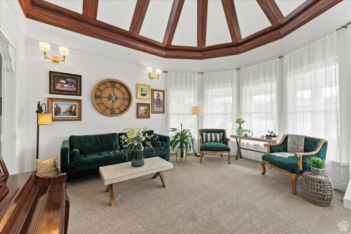 Living room featuring a notable chandelier, light colored carpet, and high vaulted ceiling