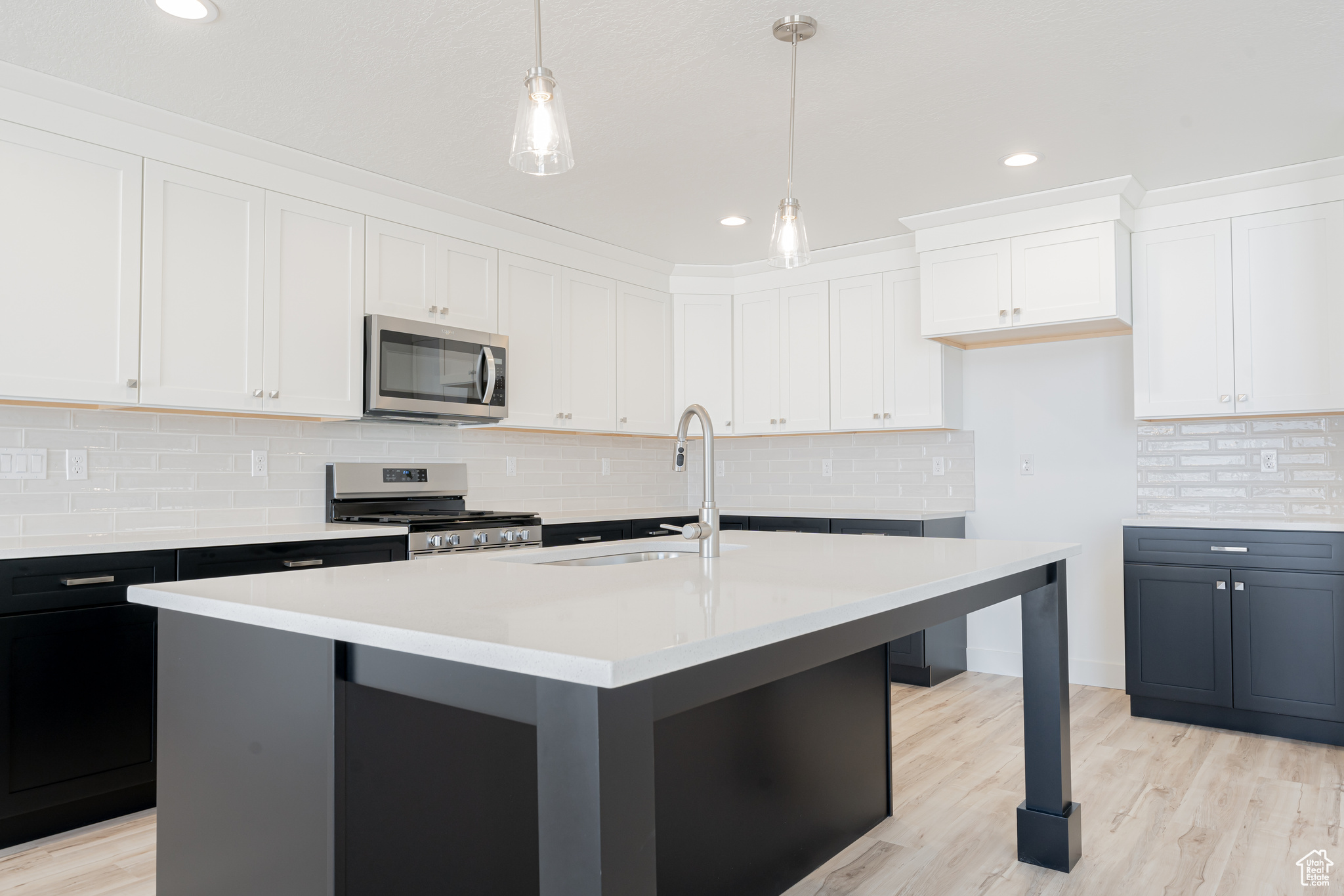 Kitchen with appliances with stainless steel finishes, light hardwood / wood-style flooring, and backsplash