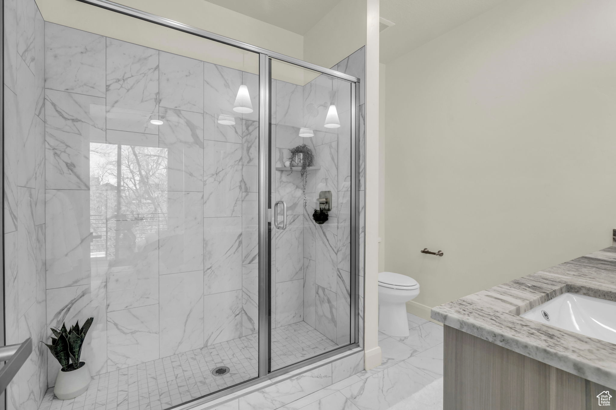 Bathroom featuring vanity, toilet, tile floors, and a shower with shower door