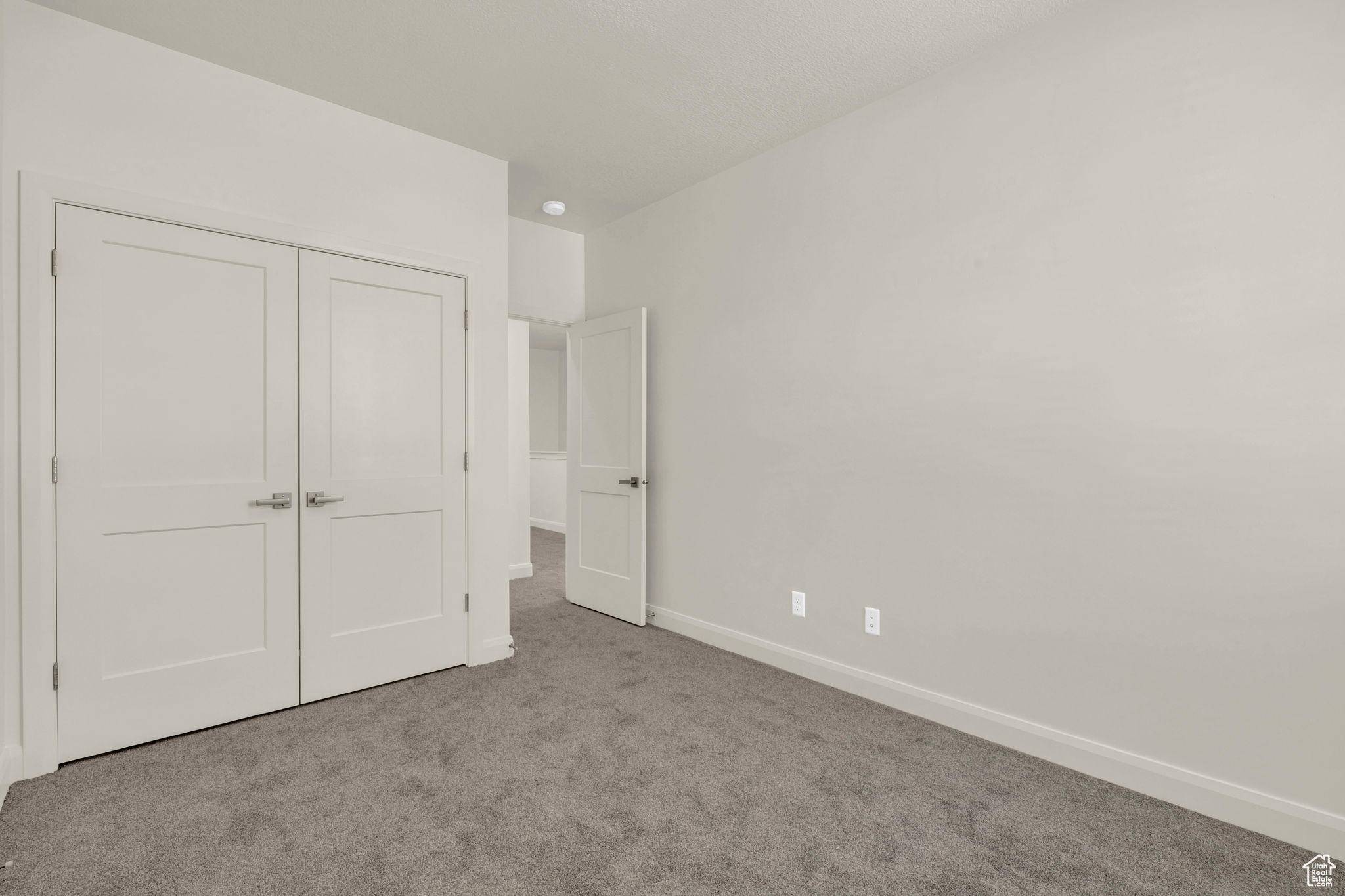 Unfurnished bedroom with light carpet and a closet