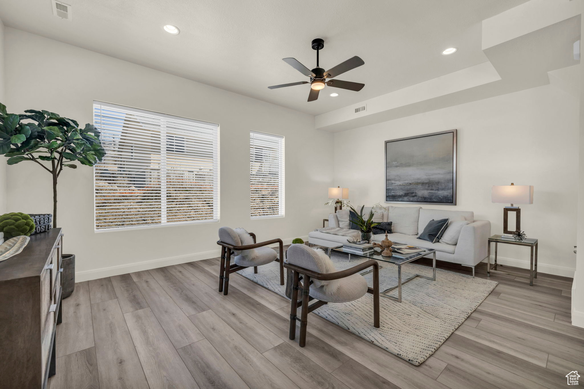 Living room featuring light hardwood / wood-style flooring, a raised ceiling, and ceiling fan