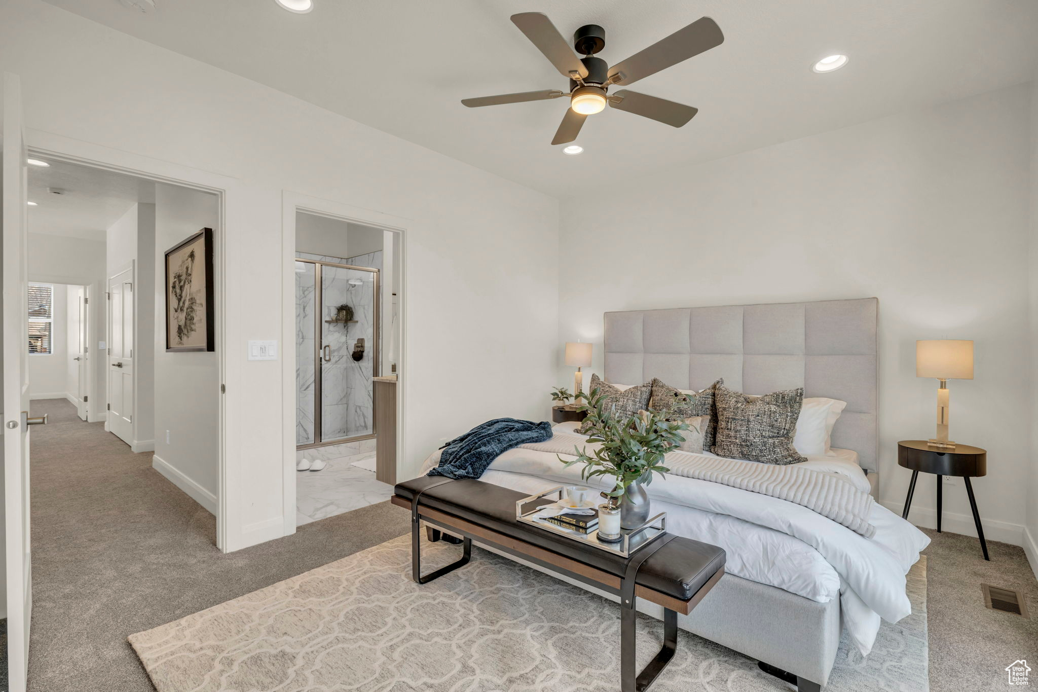 Carpeted bedroom featuring ensuite bath and ceiling fan