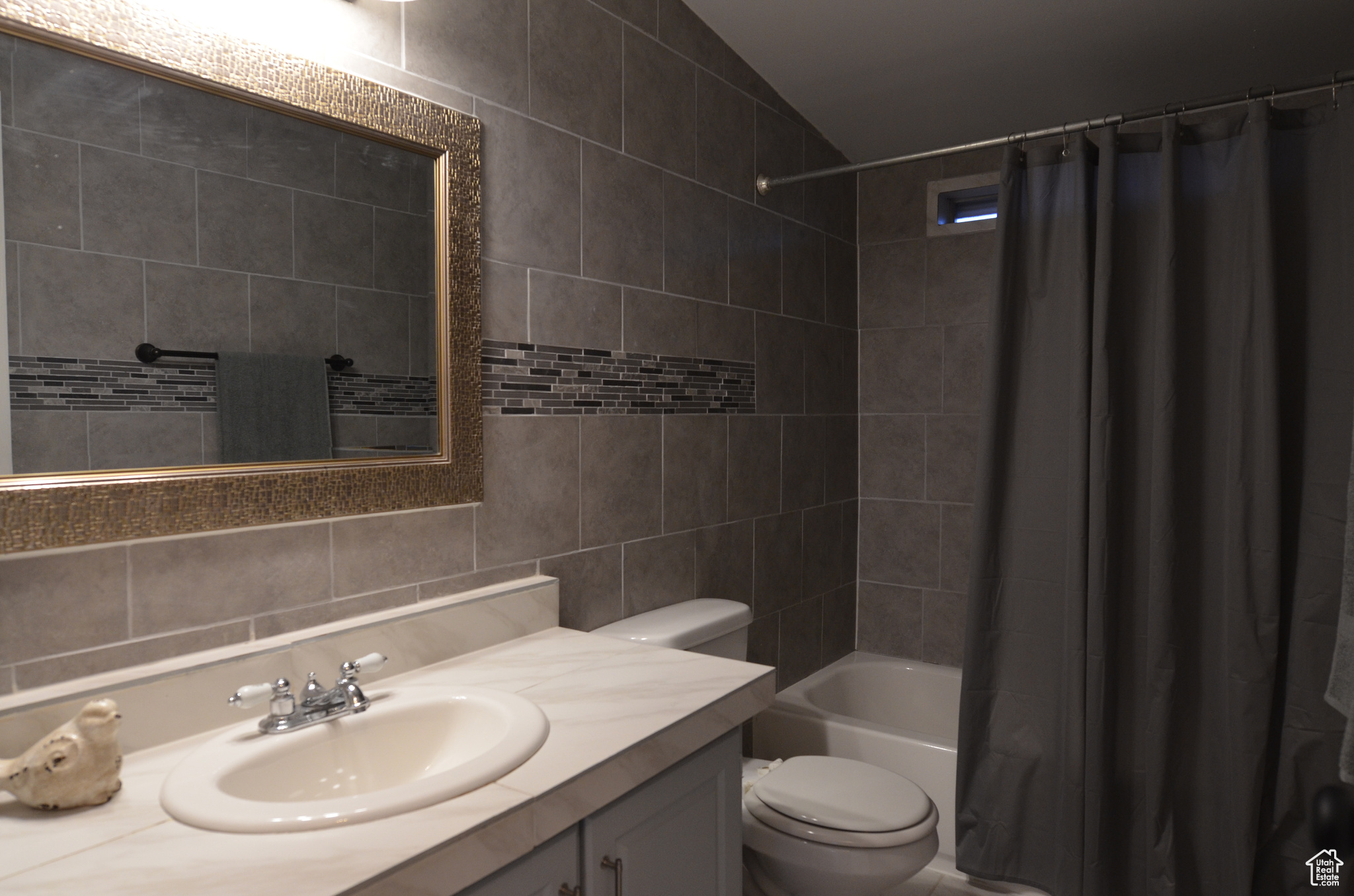 Full bathroom with vanity, toilet, shower / tub combo, and tile walls