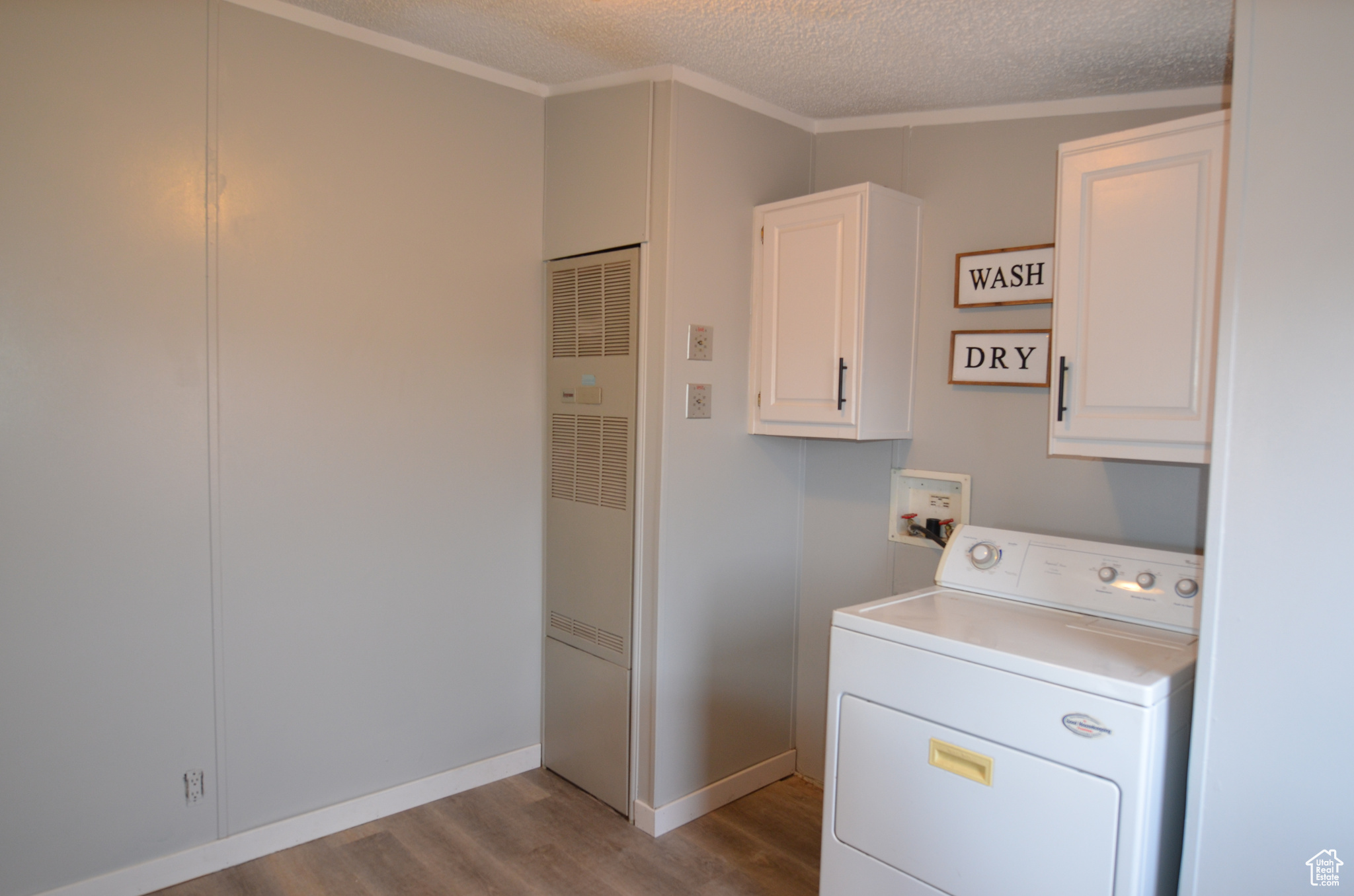 Laundry room with dryer, cabinets, a textured ceiling, and LVP flooring