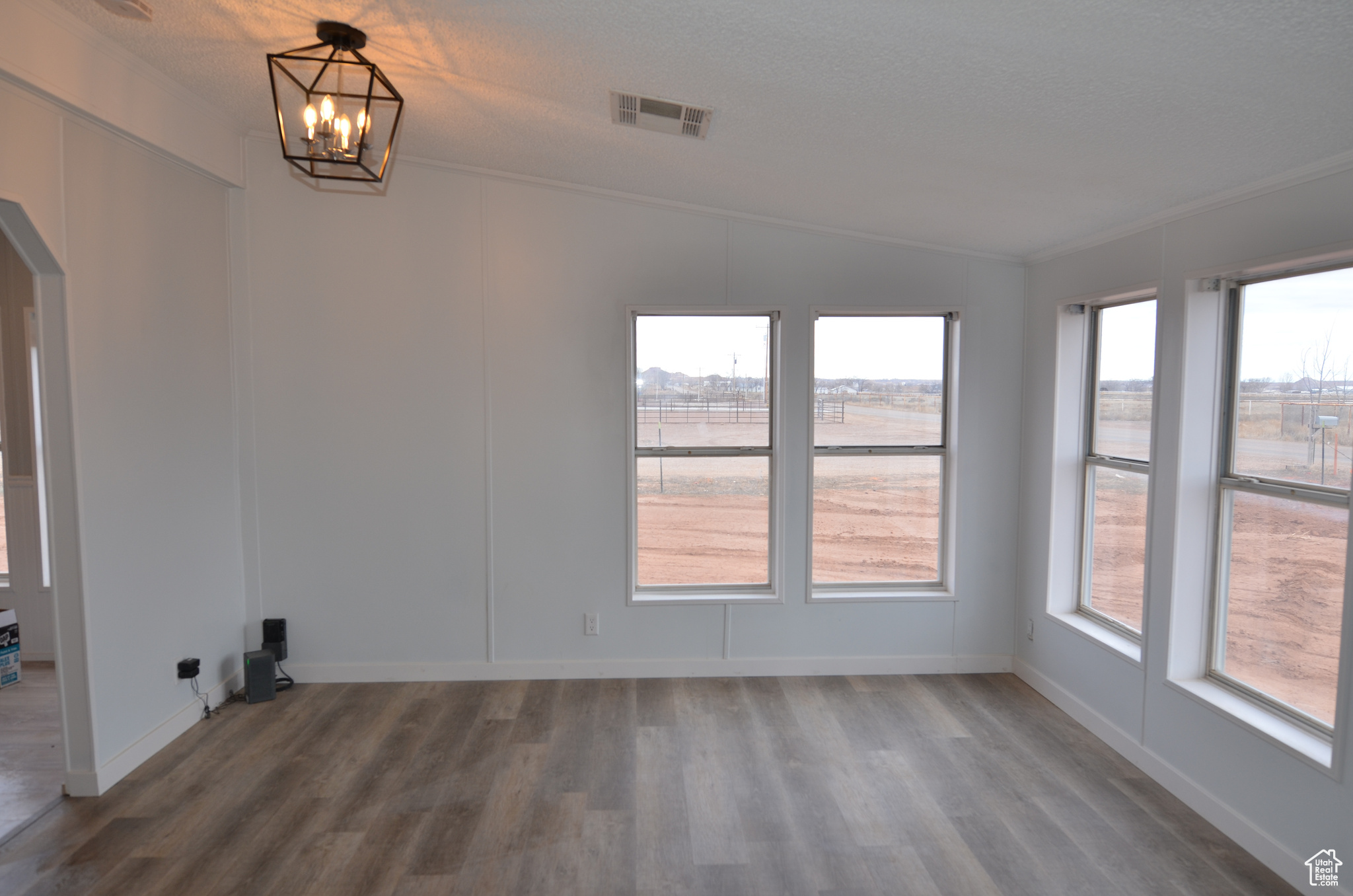 Den with ornamental molding, LVP flooring, and vaulted ceiling