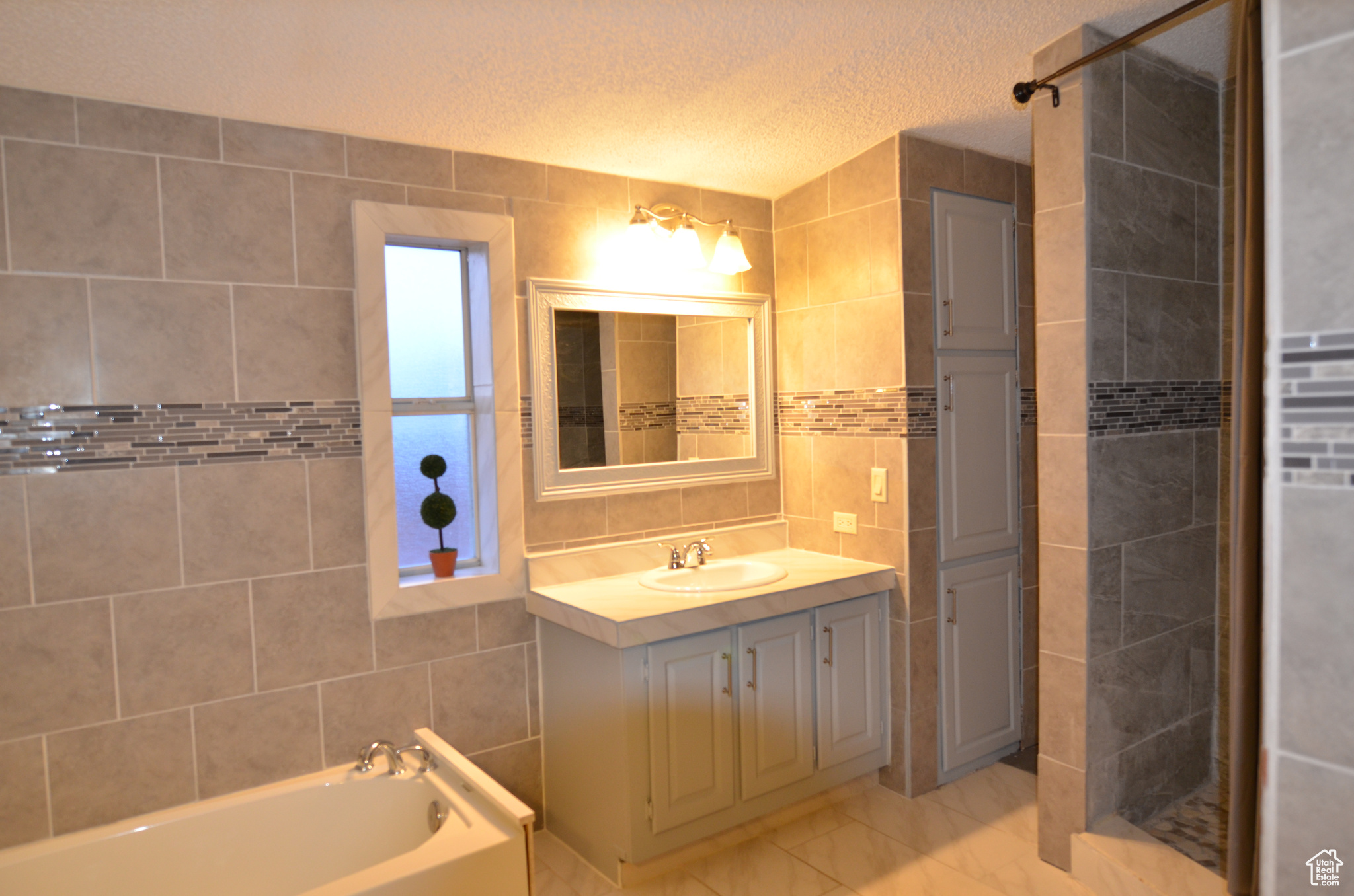 Master bathroom with tile floors, a textured ceiling, tile walls, and large vanity