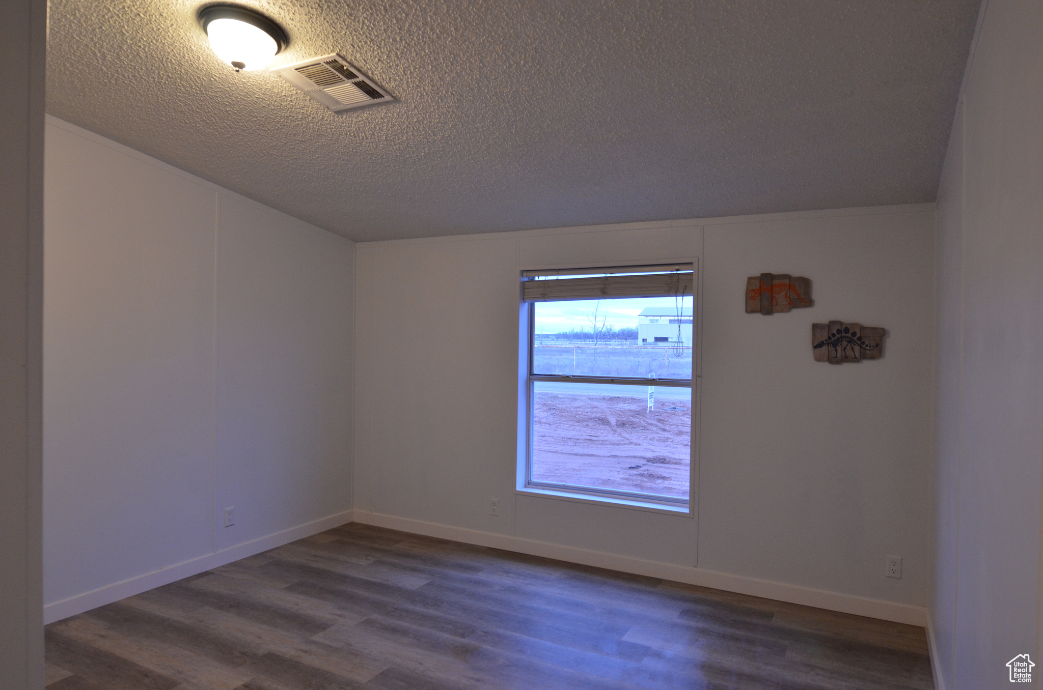 Unfurnished room with LVP and a textured ceiling