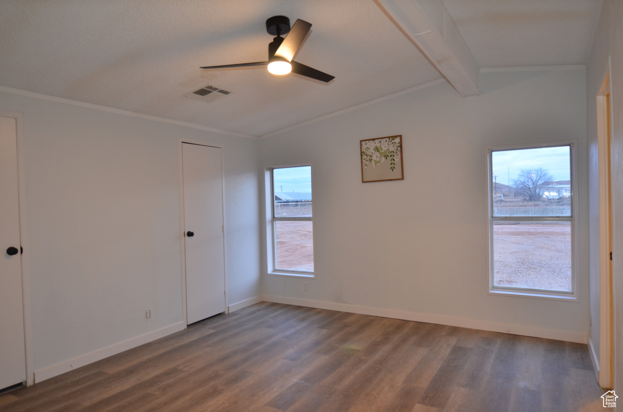 Master bedroom featuring LVP flooring, vaulted ceiling, separate walk-in closets, and ceiling fan