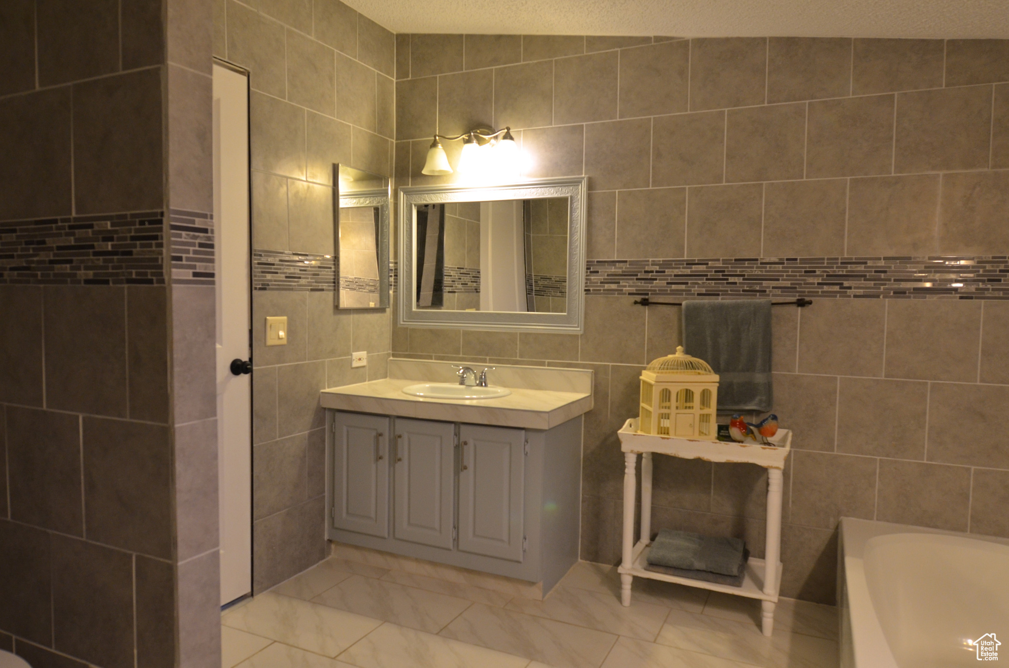 Master bathroom featuring a textured ceiling, tile walls, vanity, separate bathtub and shower, and tile flooring