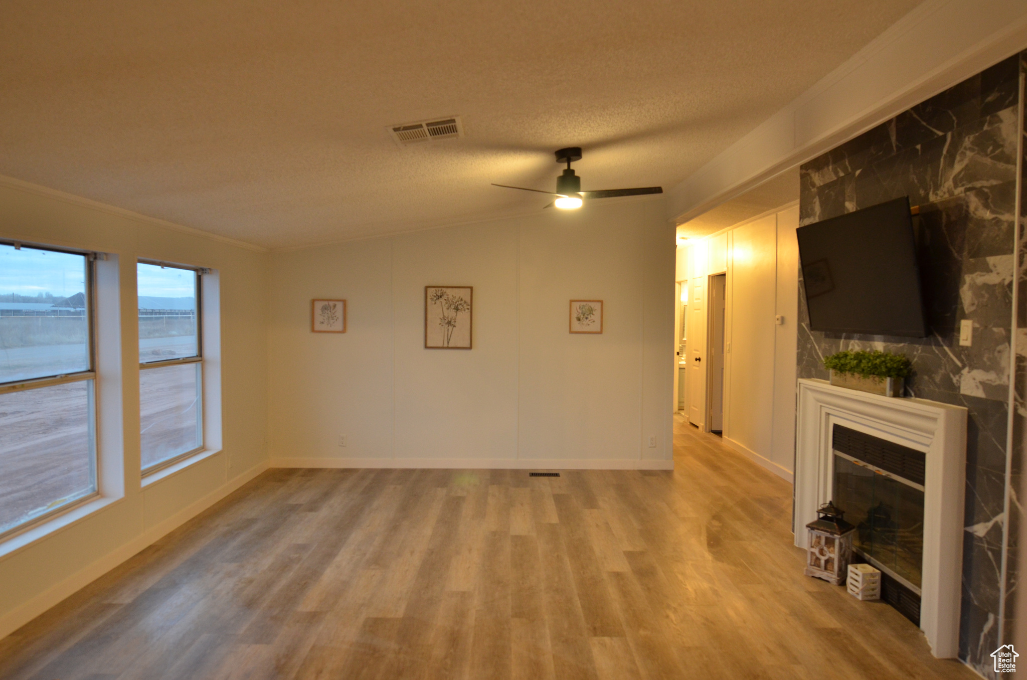 Living room with a textured ceiling, vaulted ceiling, ceiling fan, and LVP flooring