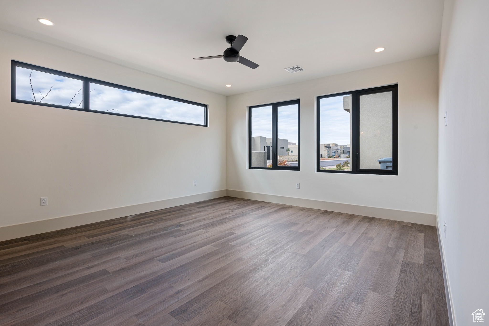 Empty room featuring dark hardwood / wood-style flooring and ceiling fan