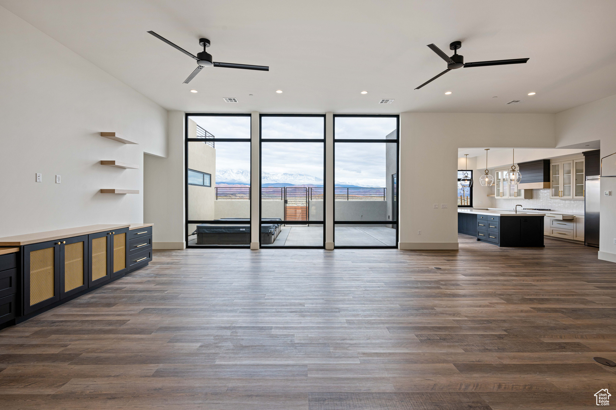 Unfurnished living room featuring dark hardwood / wood-style floors, ceiling fan with notable chandelier, and a wall of windows