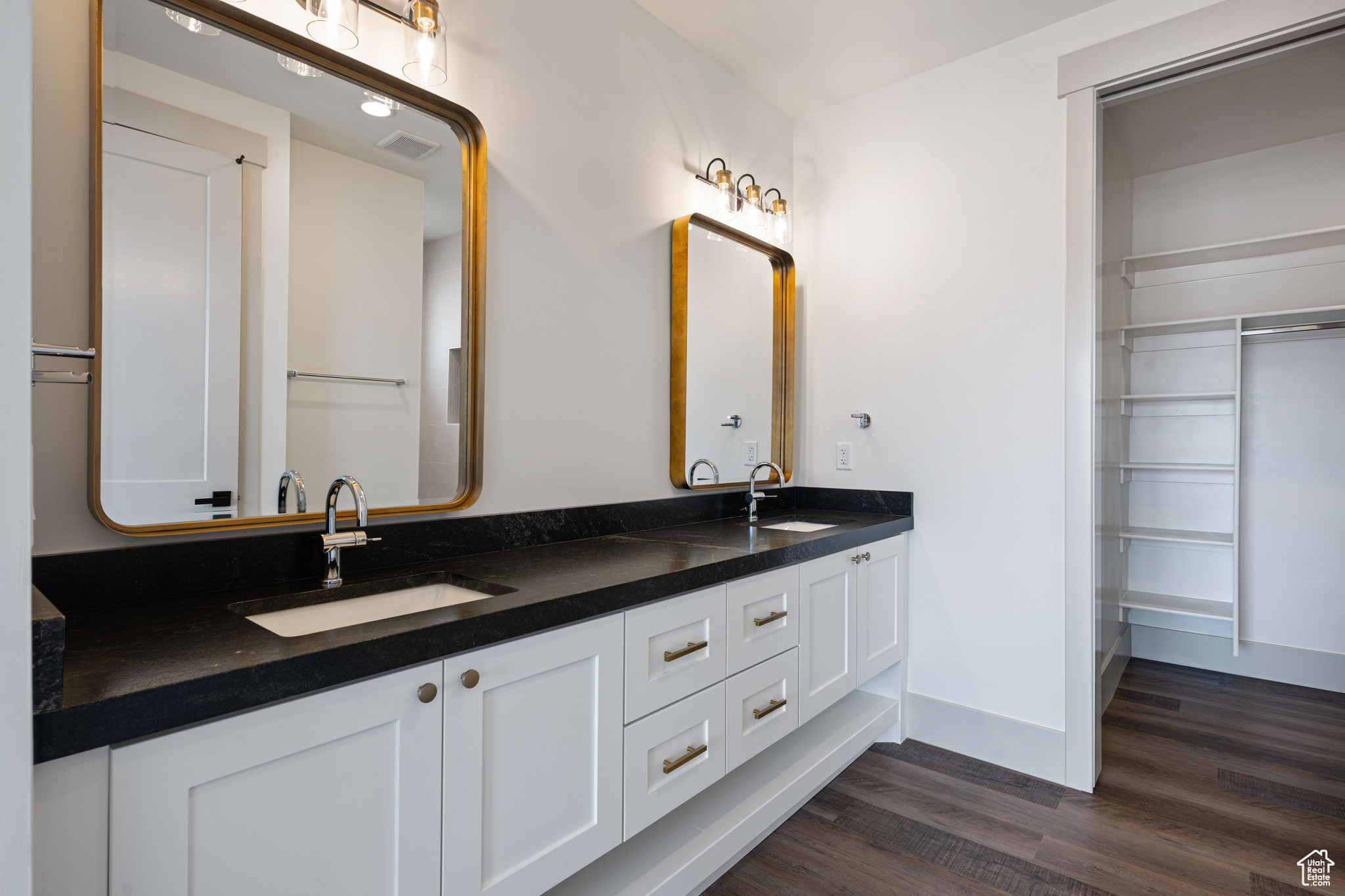 Bathroom with double vanity and hardwood / wood-style floors