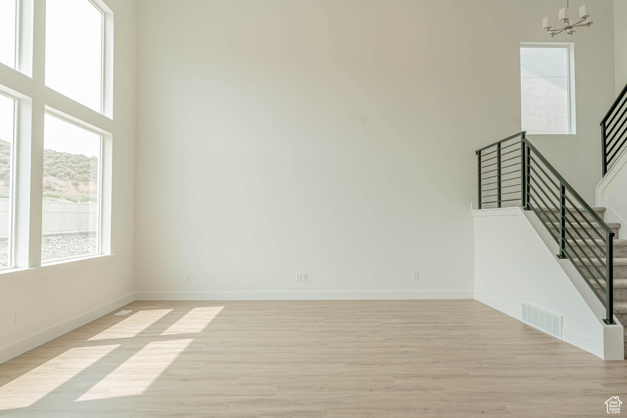 Spare room featuring a high ceiling, a chandelier, and light hardwood / wood-style flooring