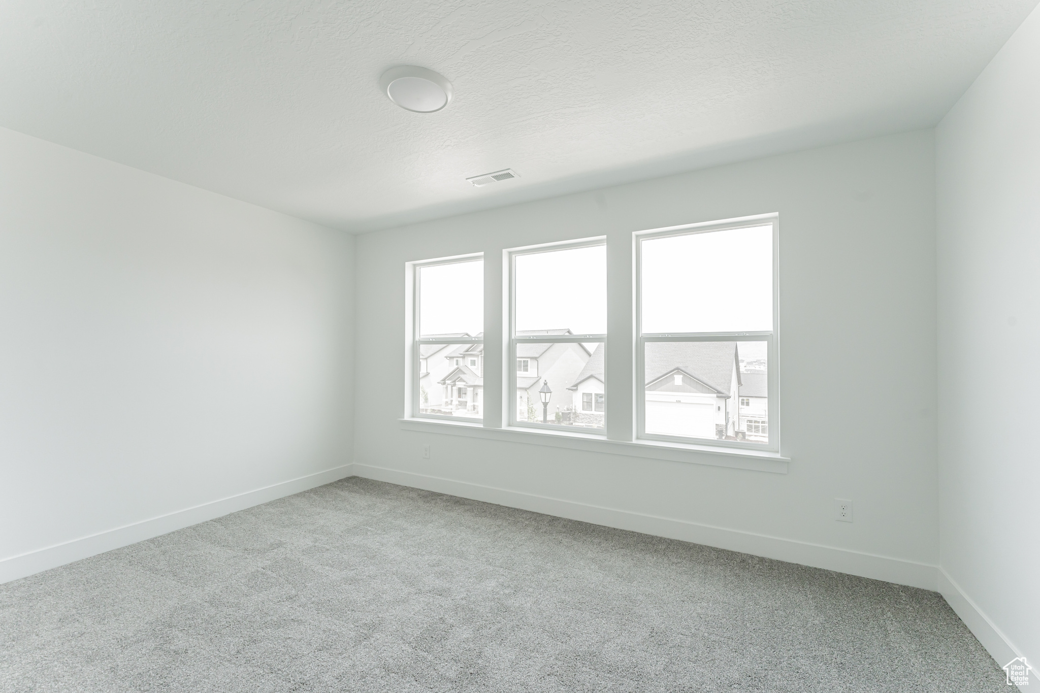 Carpeted empty room featuring a wealth of natural light