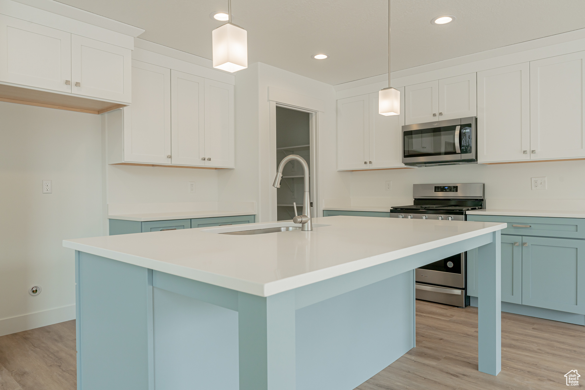 Kitchen featuring light hardwood / wood-style flooring, stainless steel appliances, and a center island with sink