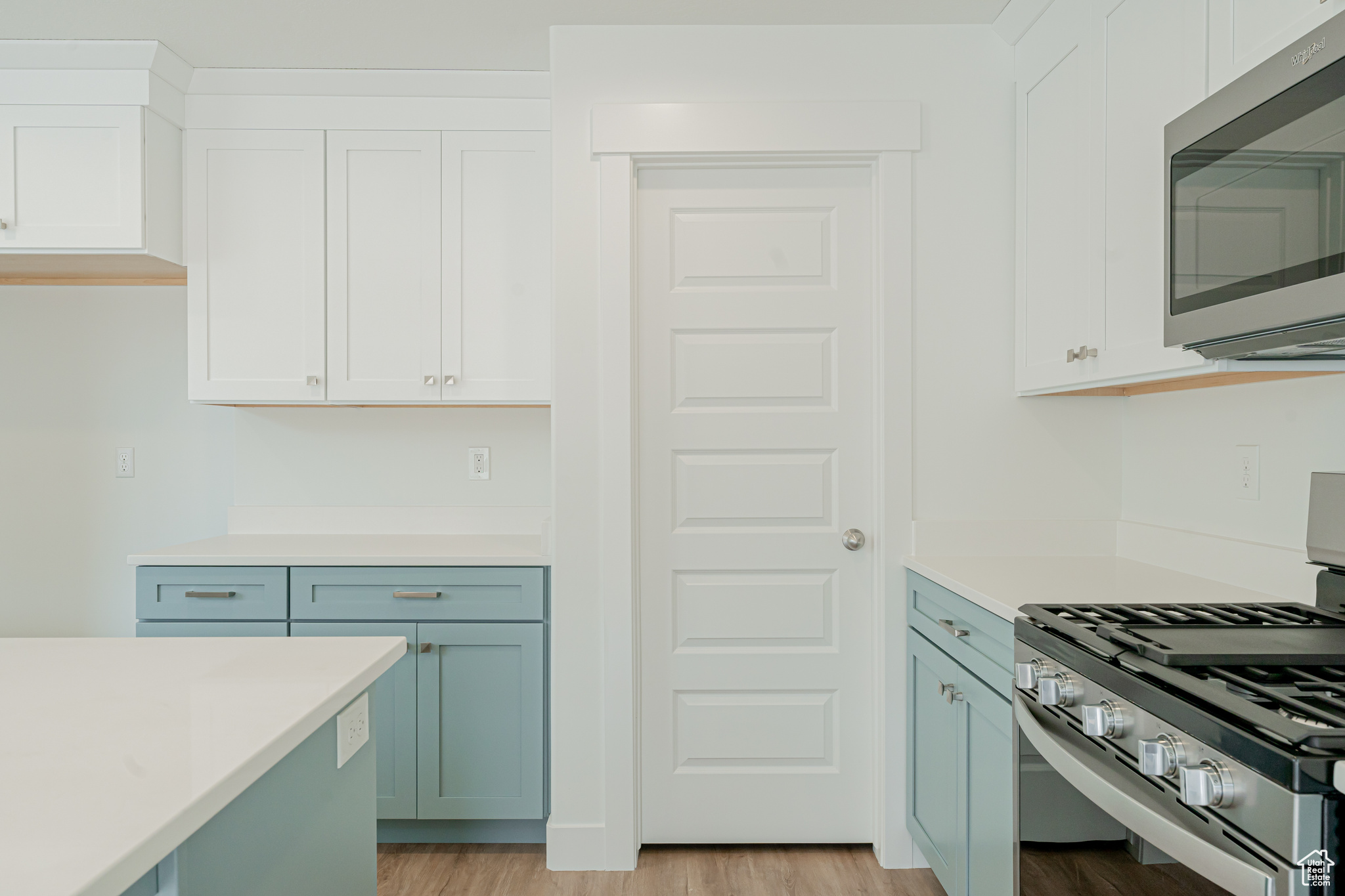 Kitchen featuring white cabinets, stainless steel appliances, and light wood-type flooring