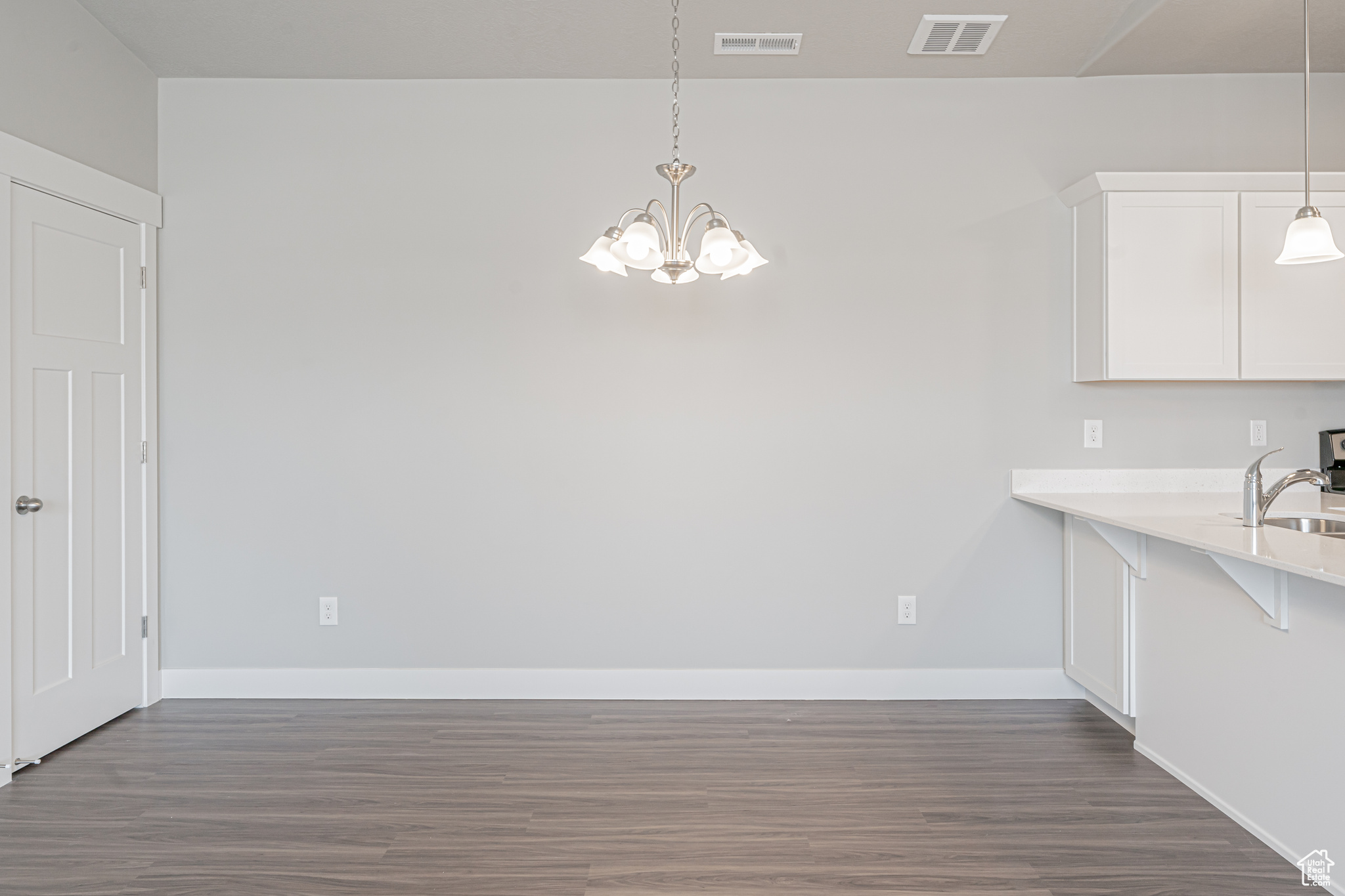 Unfurnished dining area with dark hardwood / wood-style floors, sink, and an inviting chandelier