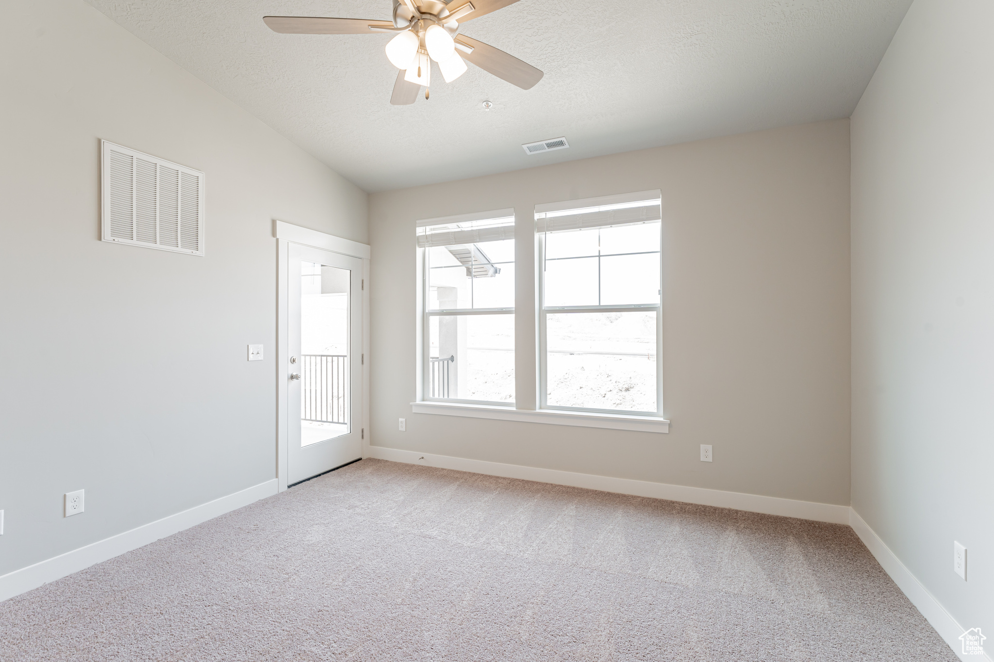 Carpeted empty room featuring ceiling fan, a textured ceiling, and vaulted ceiling