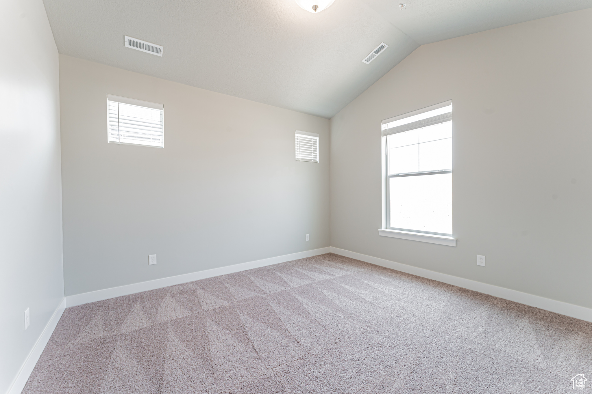 Carpeted empty room with lofted ceiling