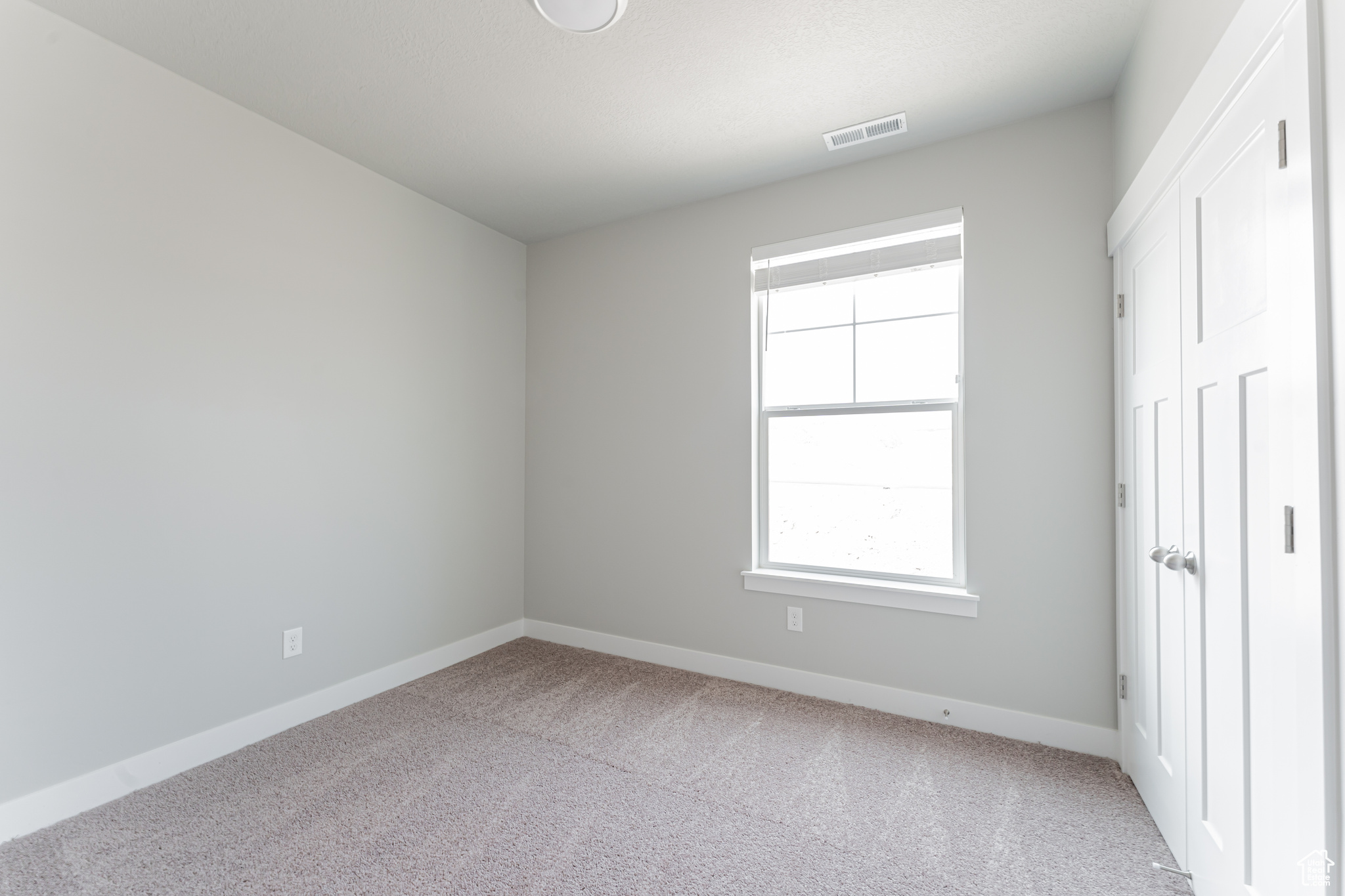 Unfurnished bedroom with light colored carpet