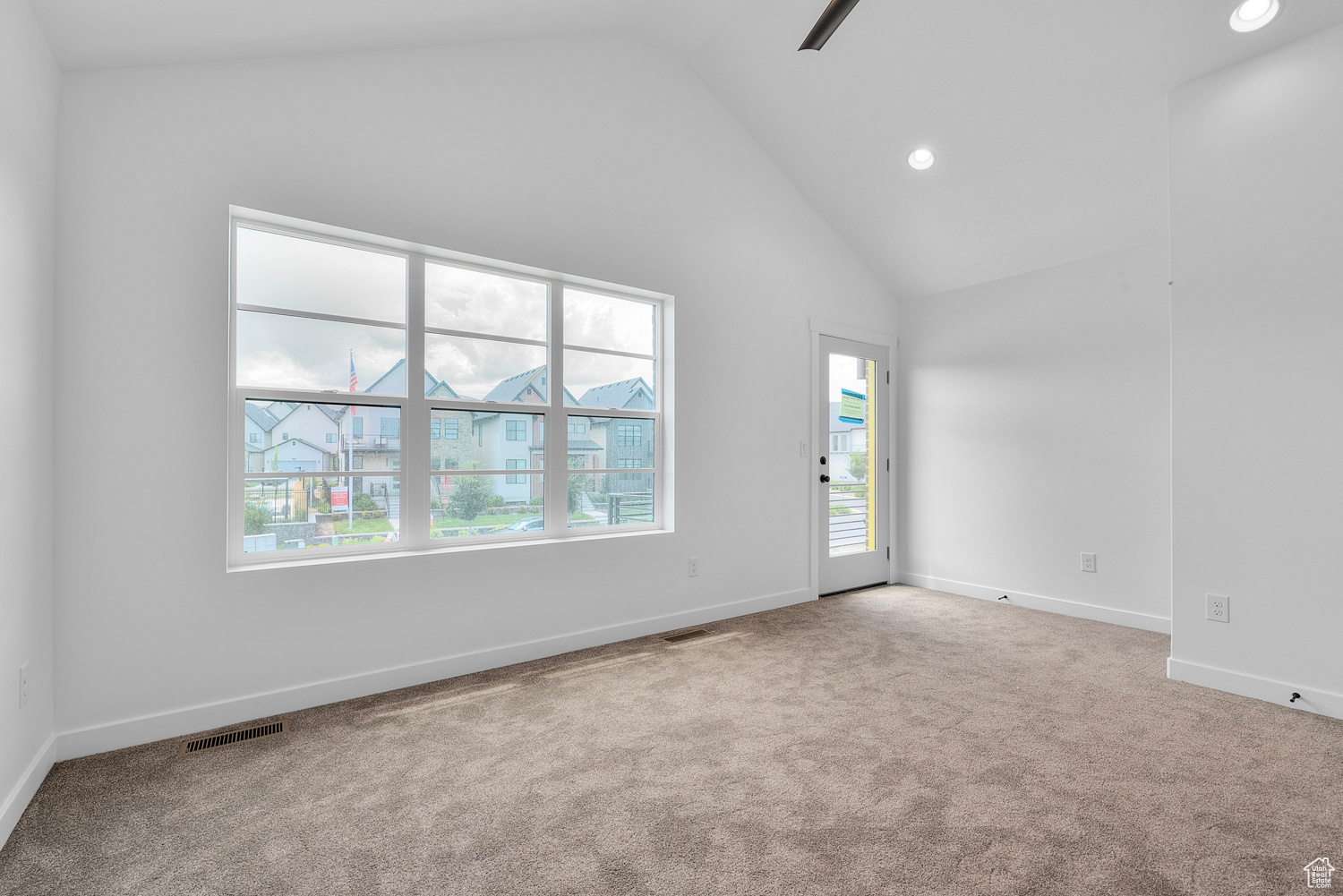 Carpeted spare room with high vaulted ceiling