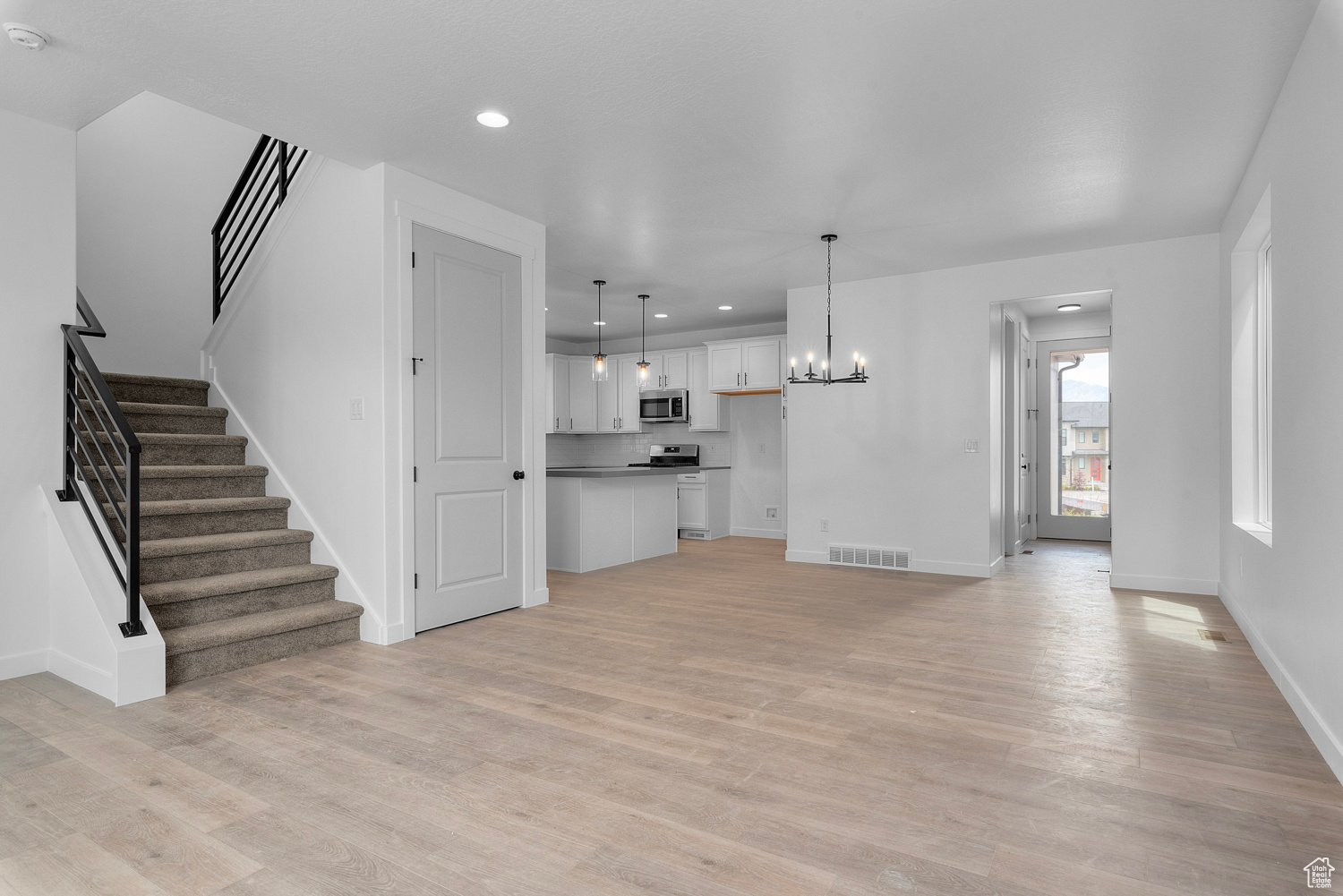 Unfurnished living room with a notable chandelier and light hardwood / wood-style flooring