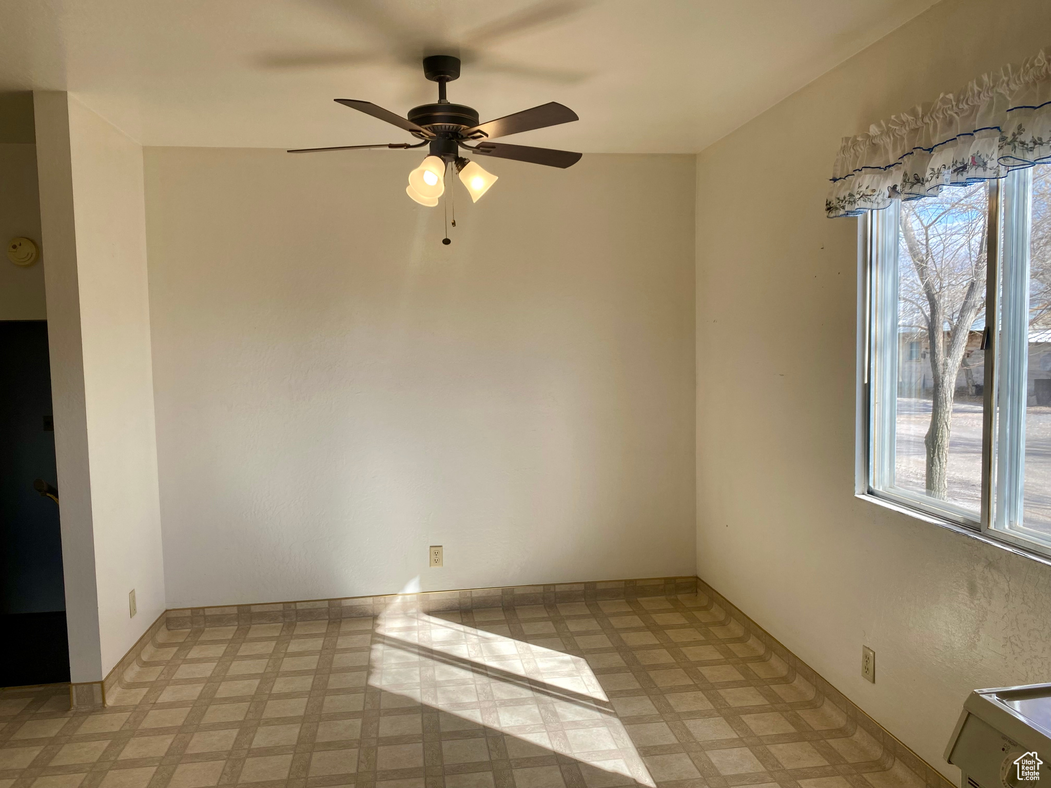 Empty room featuring light tile flooring and ceiling fan