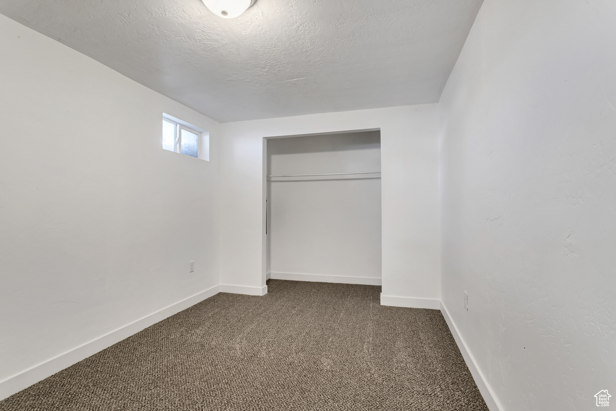 Unfurnished bedroom with dark colored carpet, a closet, and a textured ceiling