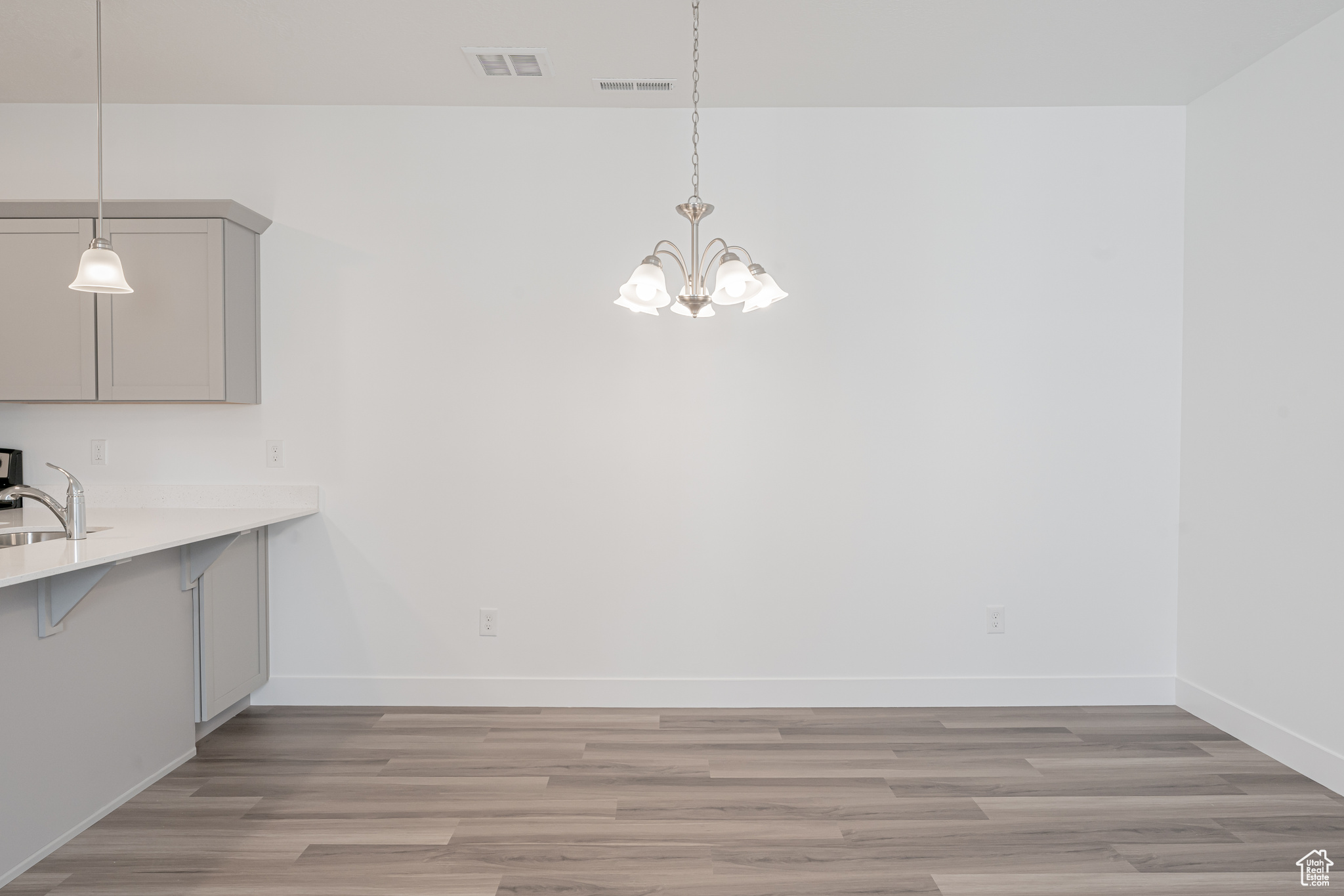 Unfurnished dining area with sink, light hardwood / wood-style flooring, and a chandelier