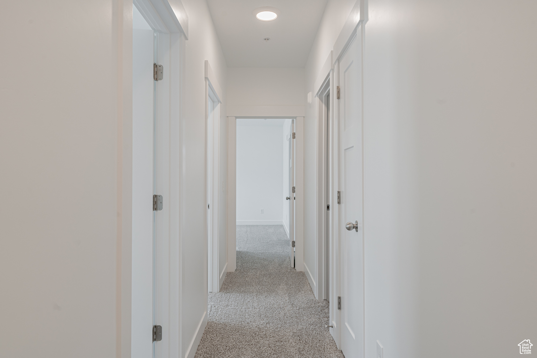 Hallway featuring light carpet